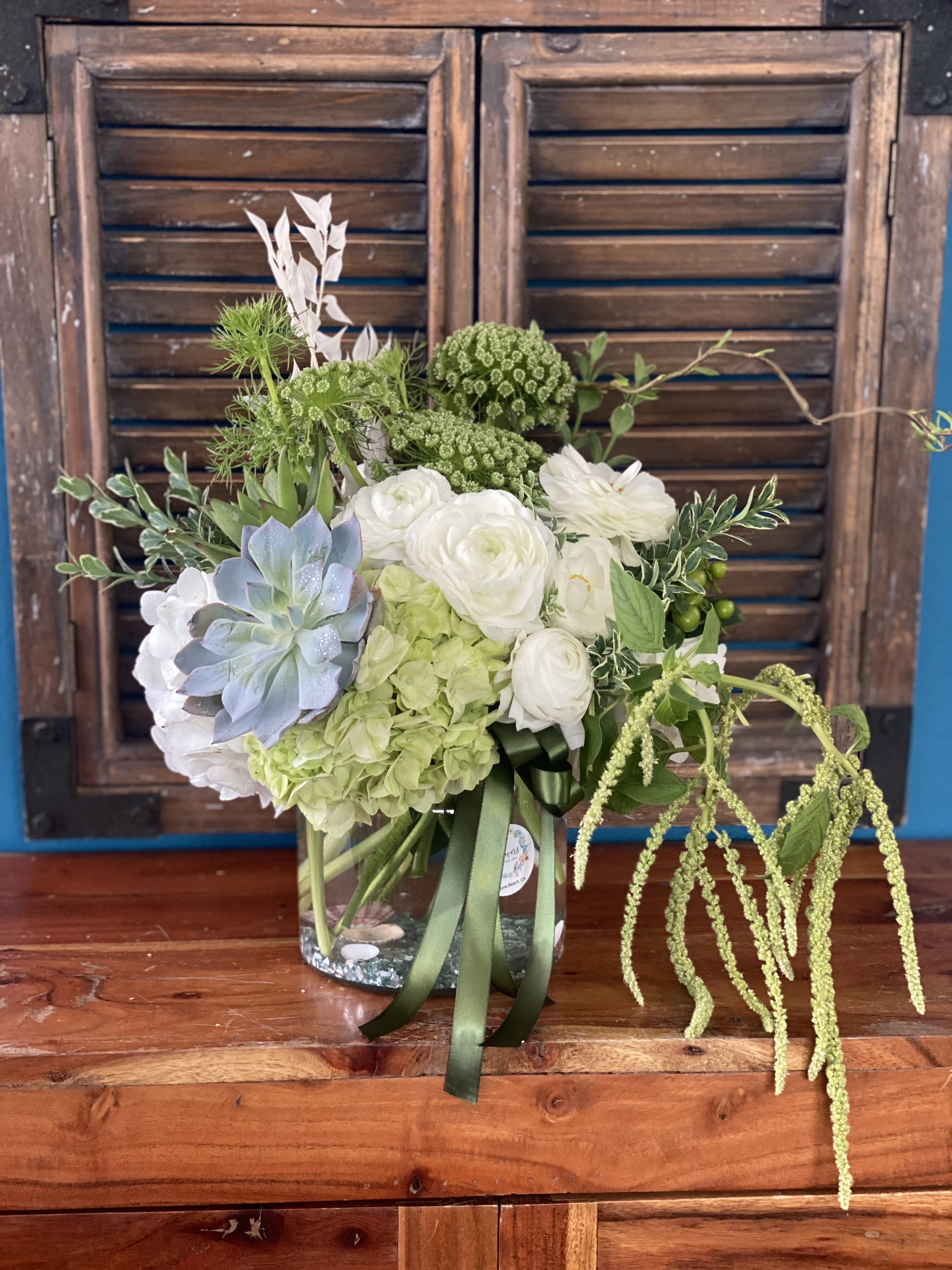 Mixed floral arrangement in a clear glass vase with white and green blooms