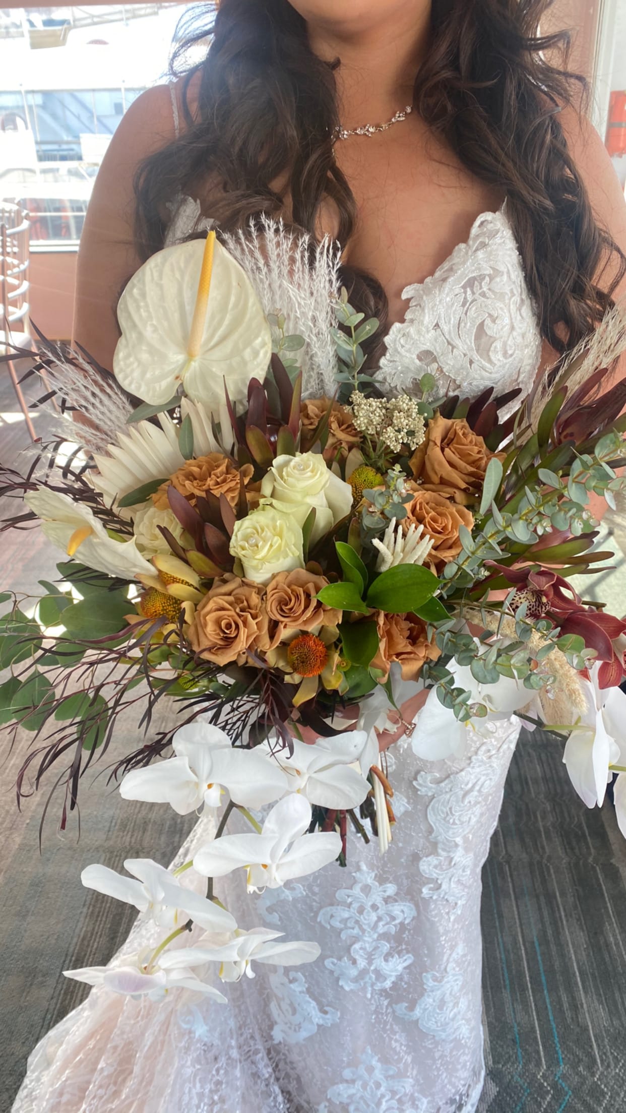 Bride holding a large bouquet with white orchids and tan roses