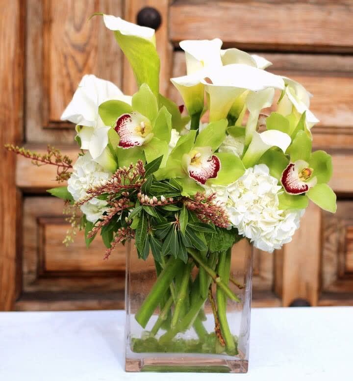 White calla lilies and orchids in a clear glass vase