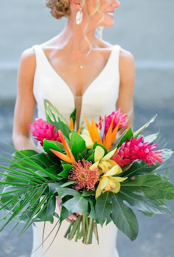 Bride holding a tropical bouquet with pink, orange, and yellow flowers