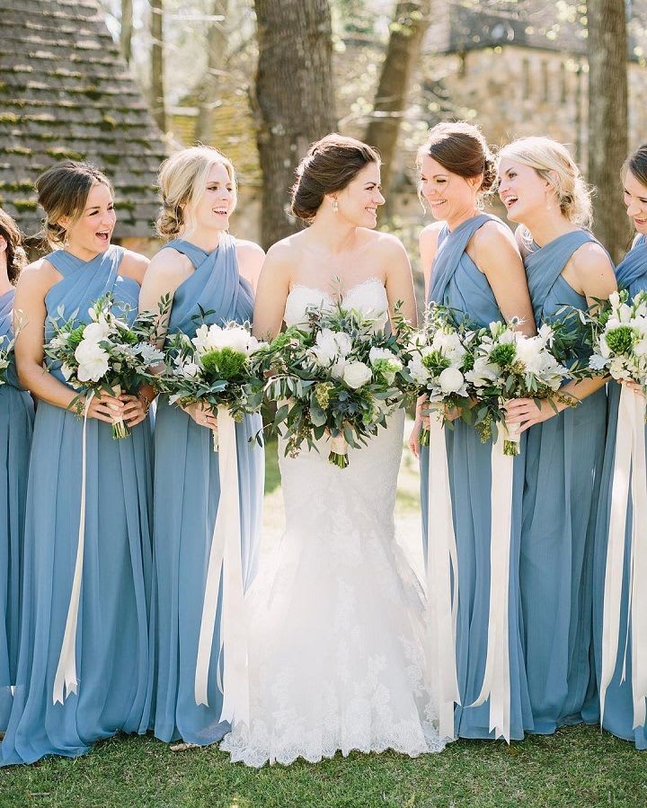 Bride and bridesmaids holding white and green bouquets outdoors