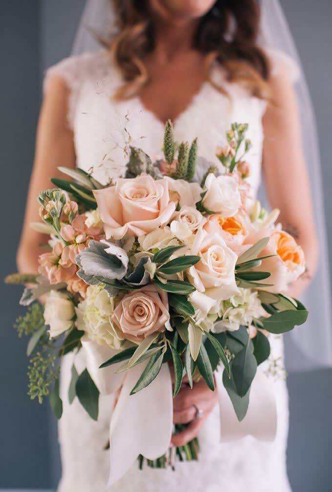 Bridal hand-tied bouquet of peach and cream roses with white blooms and ribbon wrap