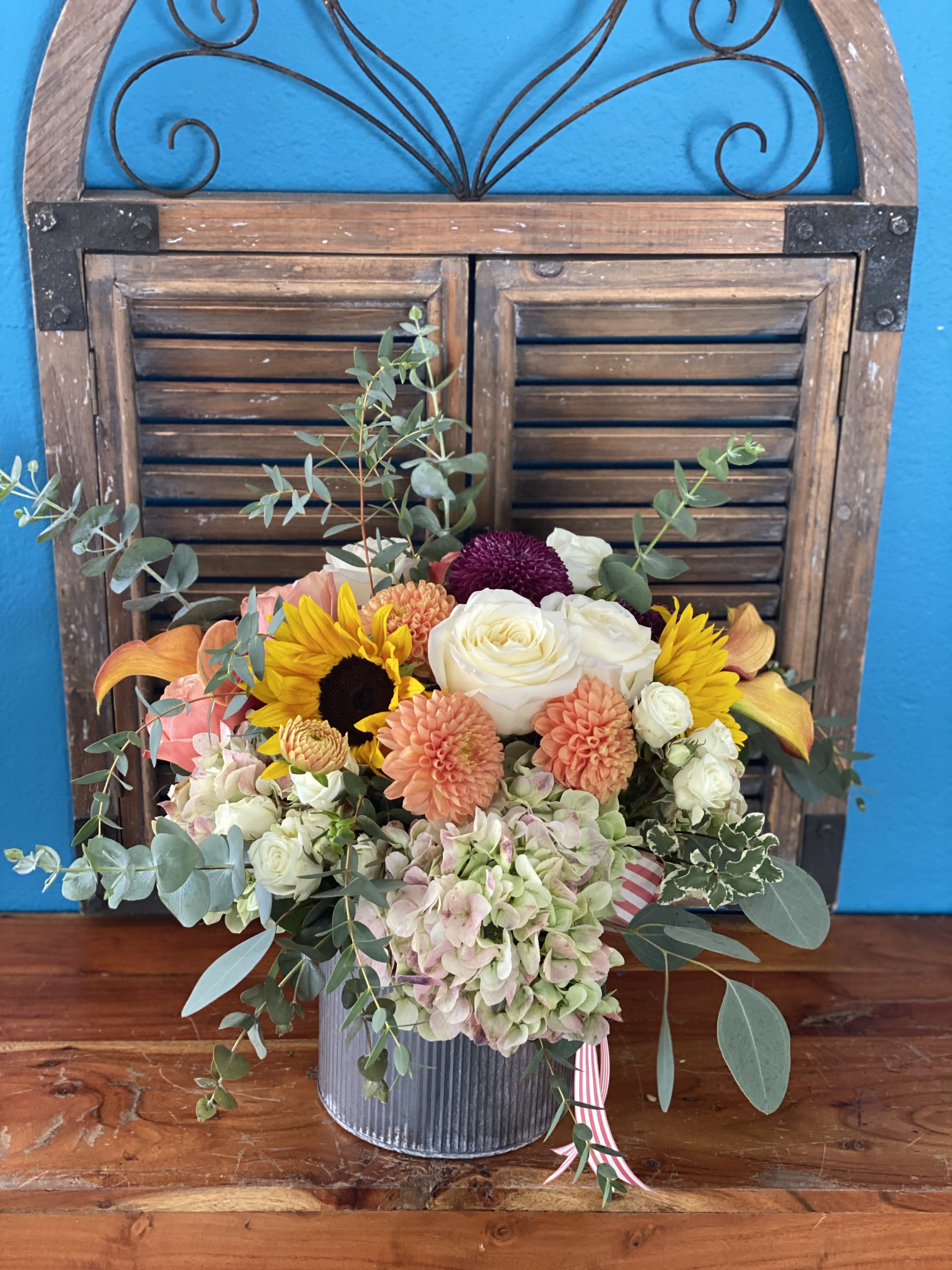 Mixed bouquet in a ribbed metal container with roses, dahlias, sunflowers, and hydrangeas