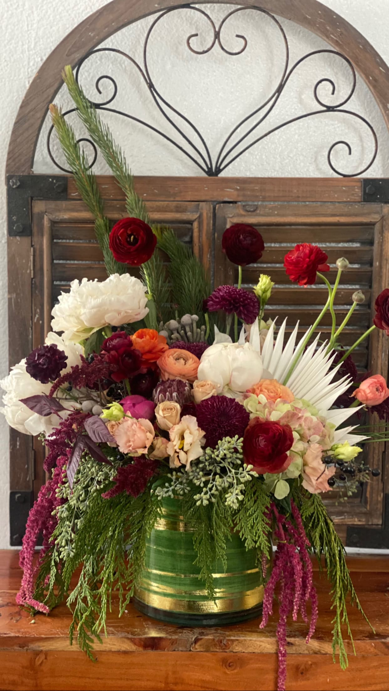 Mixed bouquet in a green-and-gold vase with red, white, and purple flowers