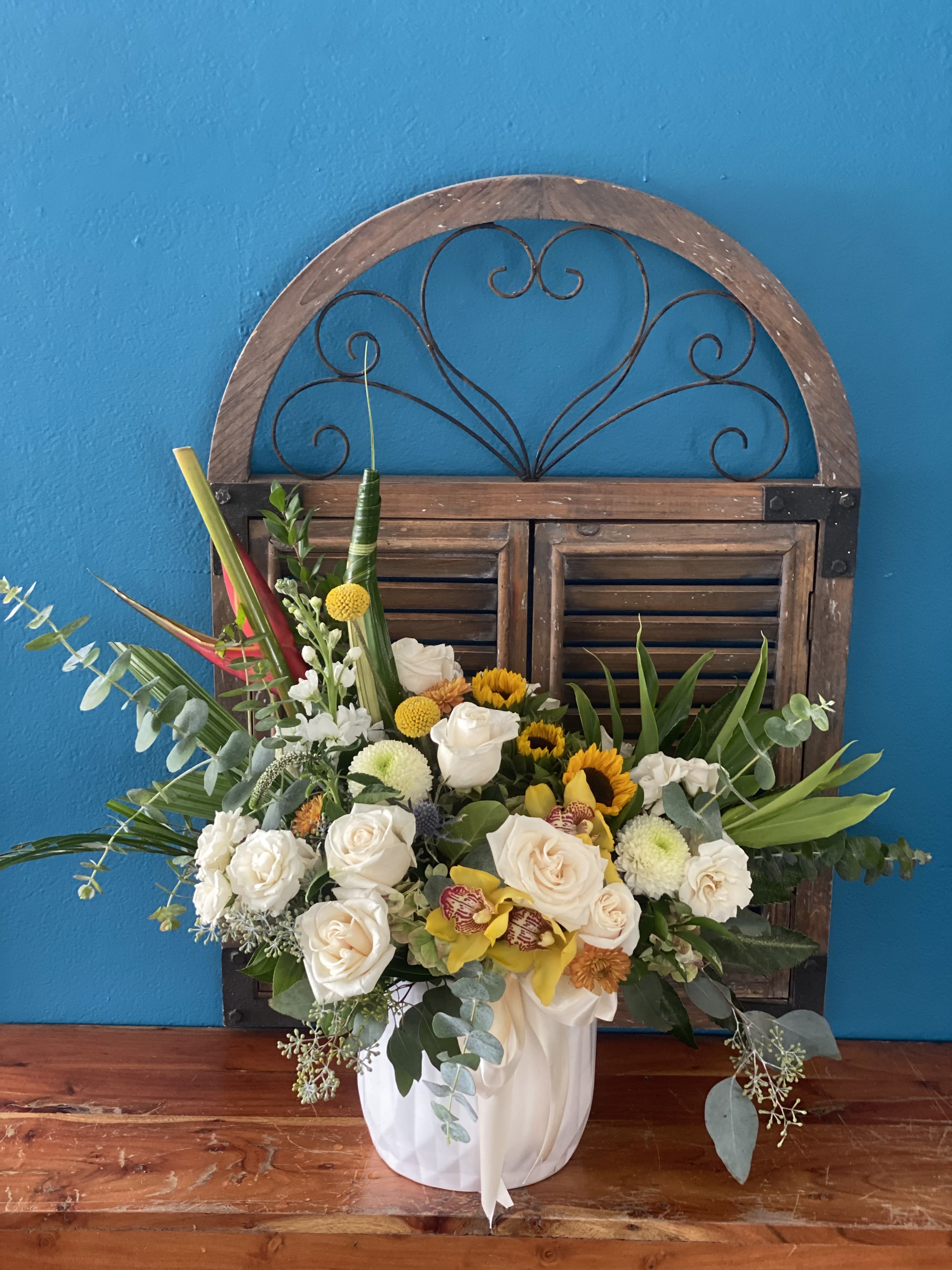 White roses and sunflowers in a white vase with greenery