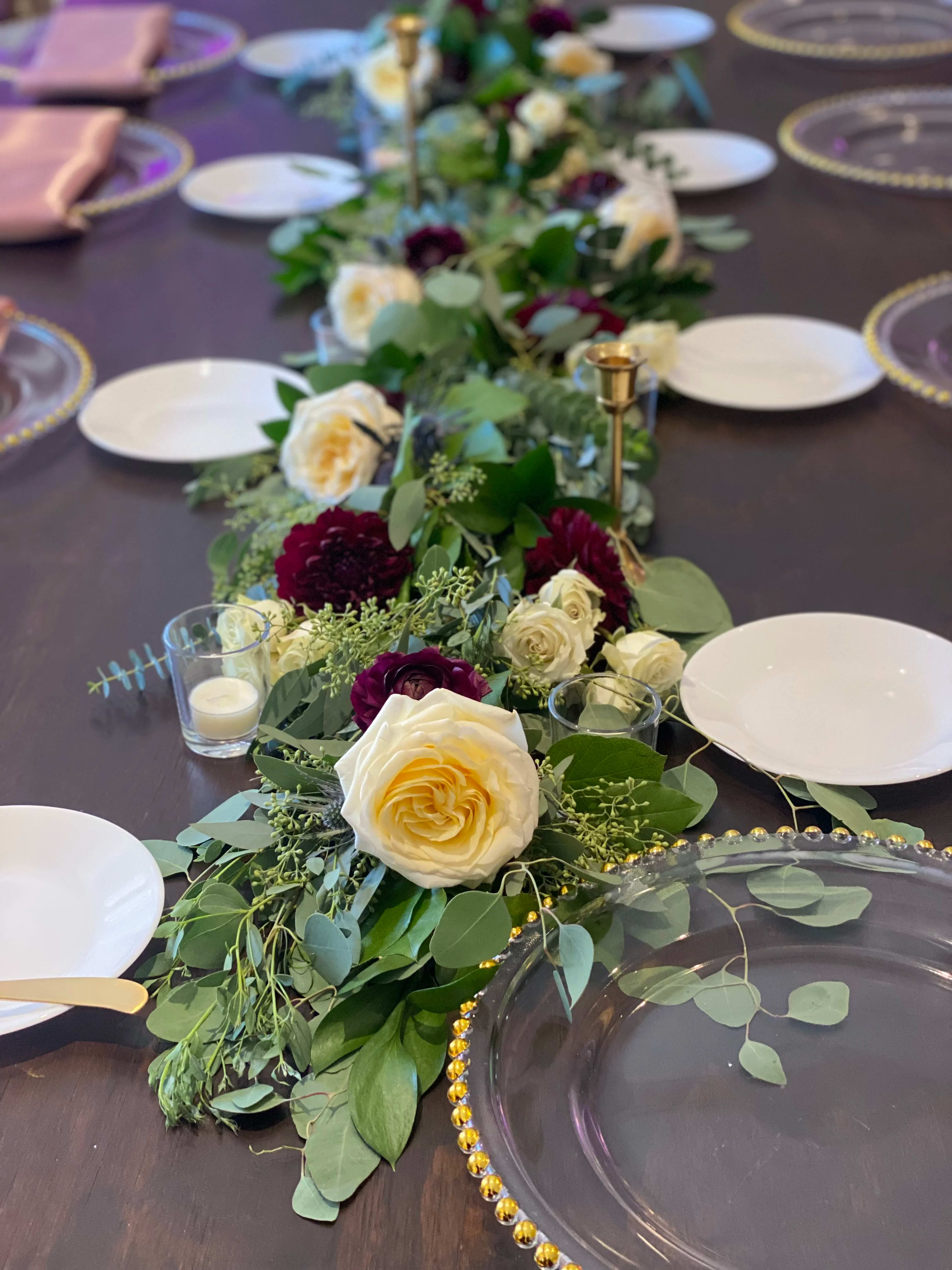 Long floral table runner with cream and burgundy roses on a dining table