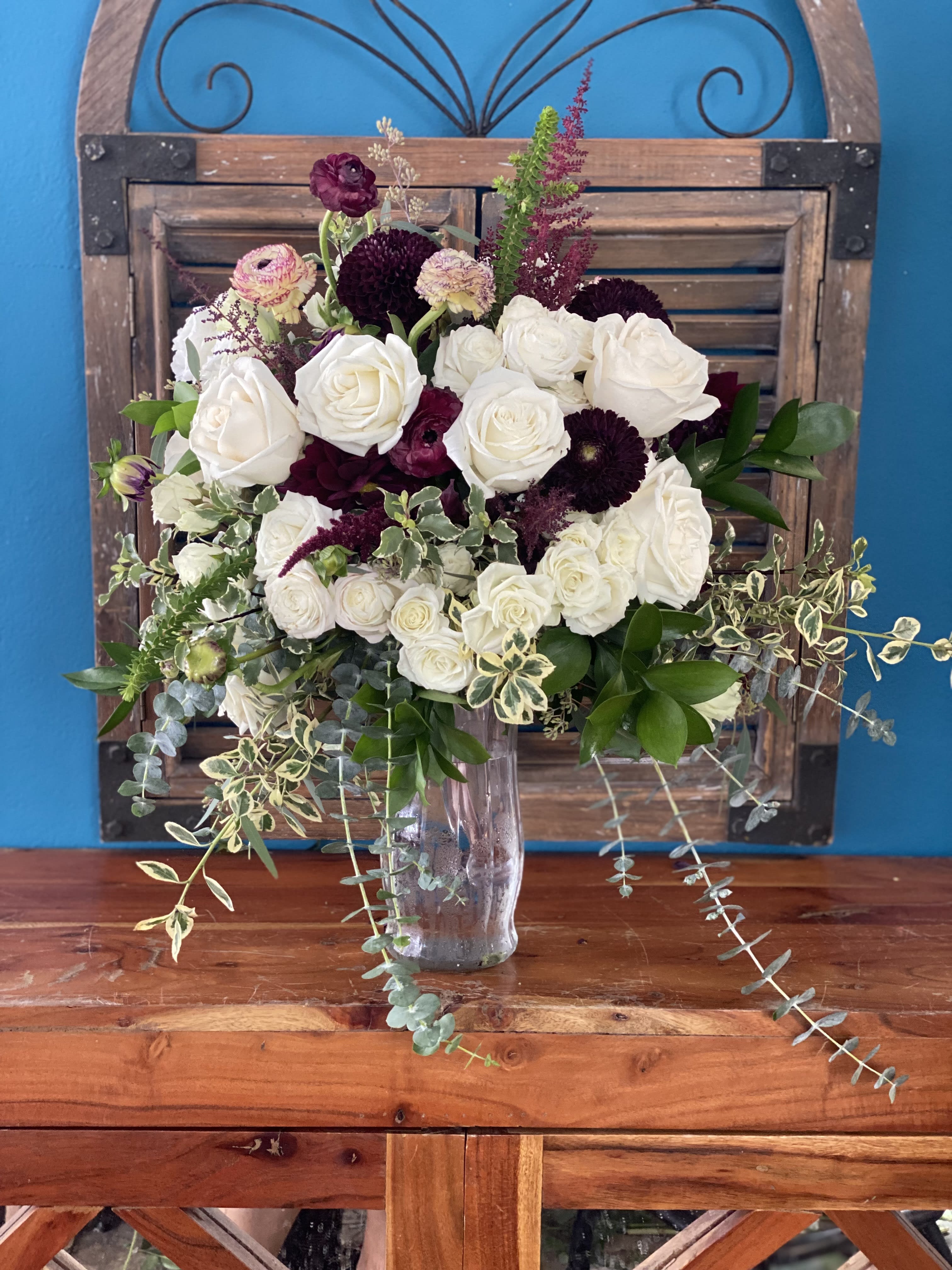 White and burgundy rose bouquet in a clear glass vase