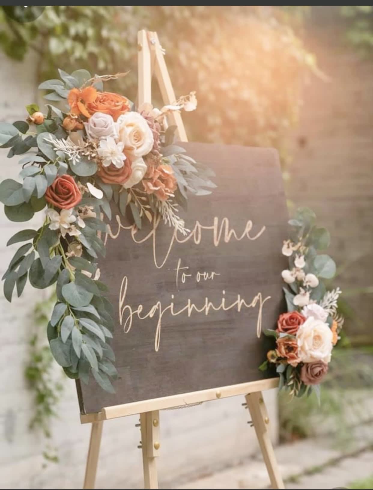 Floral welcome sign on an easel with roses and greenery
