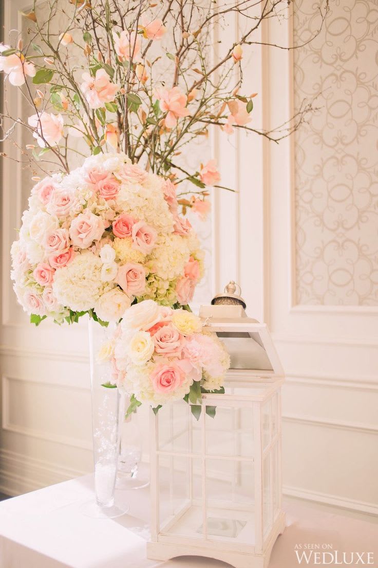 Tall pastel floral arrangement with pink roses and white blooms in a clear vase