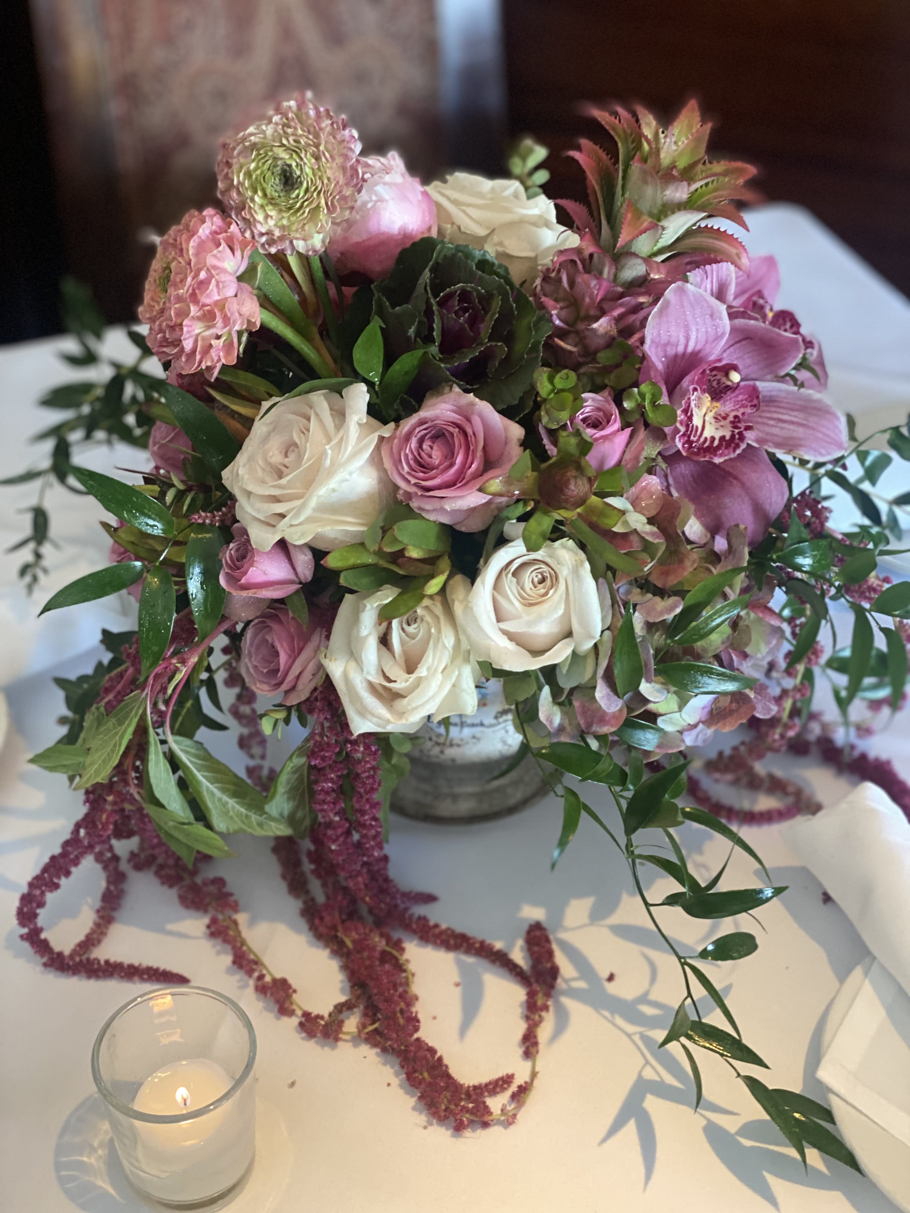 Pink and white floral centerpiece in a low vase with a candle nearby