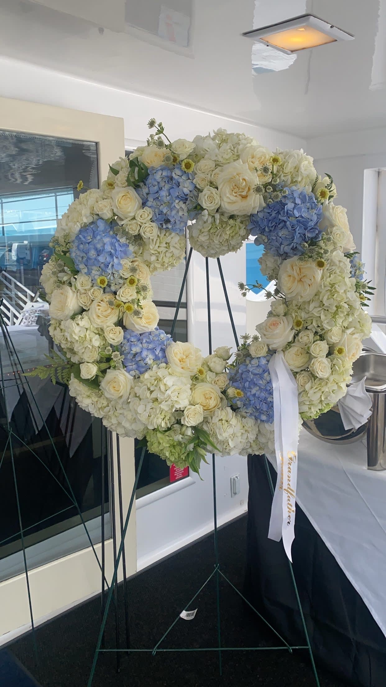 Large floral wreath of white and blue blooms on a stand