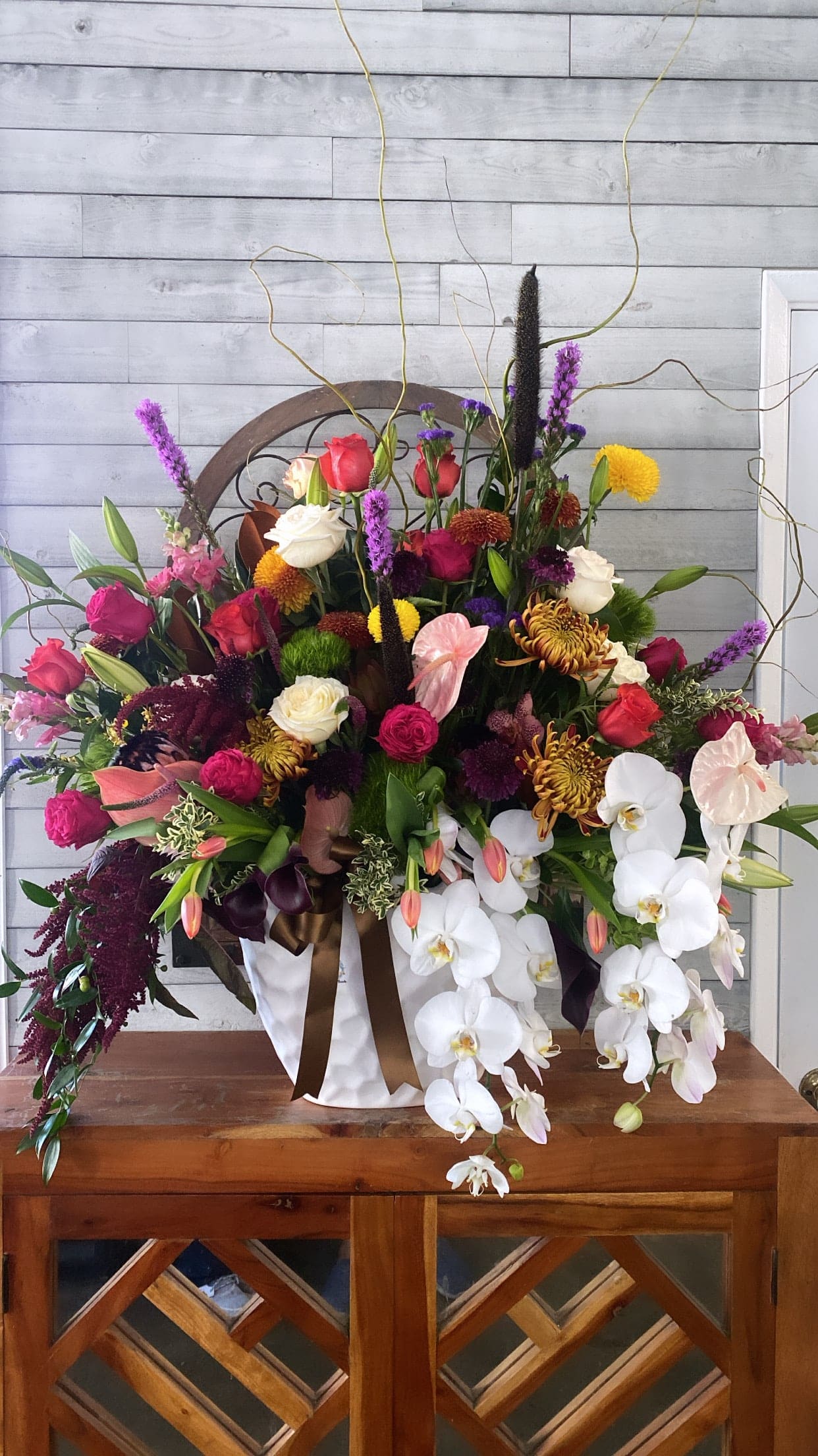 Large mixed floral arrangement with white orchids and colorful roses