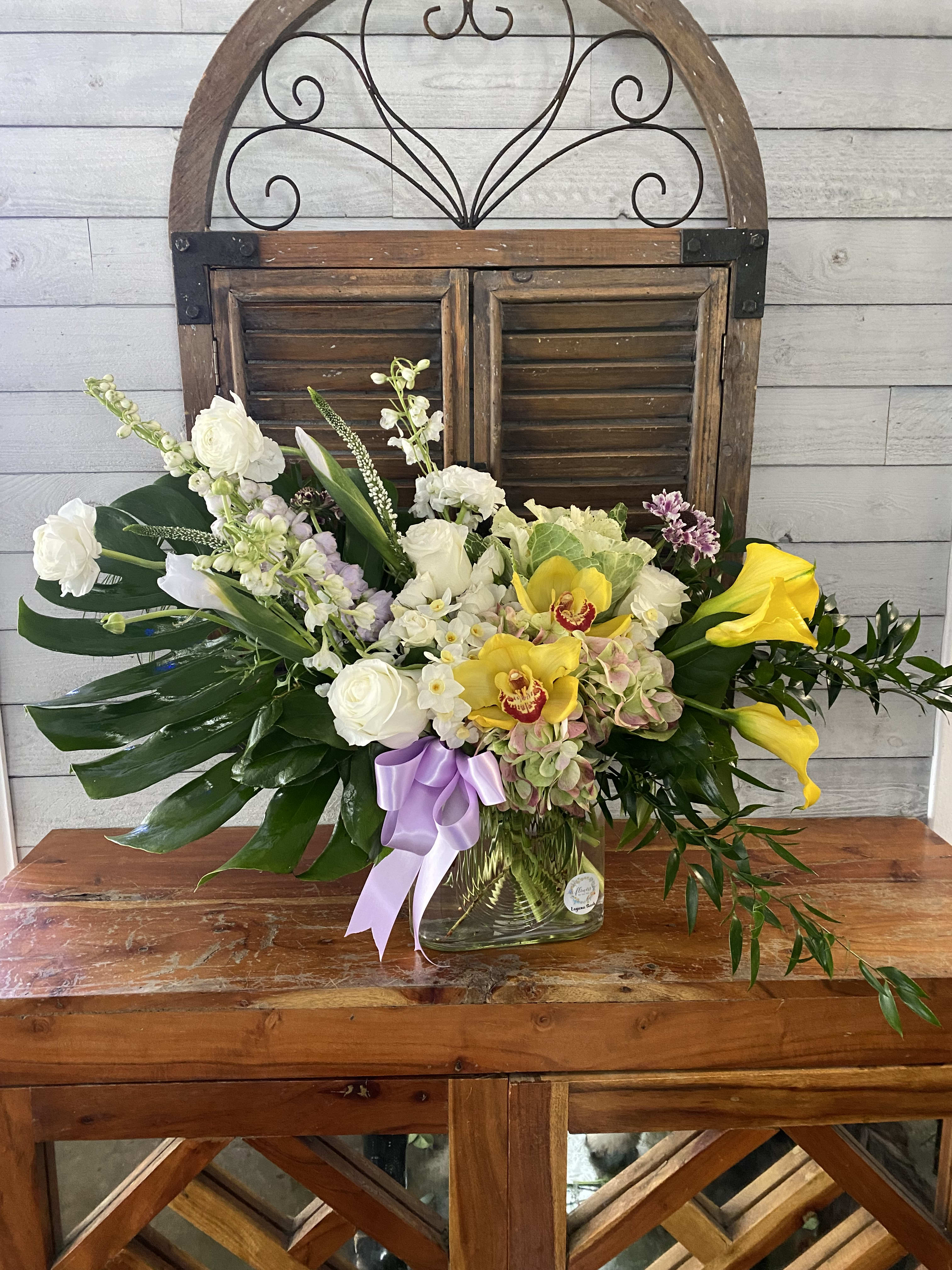 Mixed floral arrangement in a glass vase with white, yellow, and lavender blooms