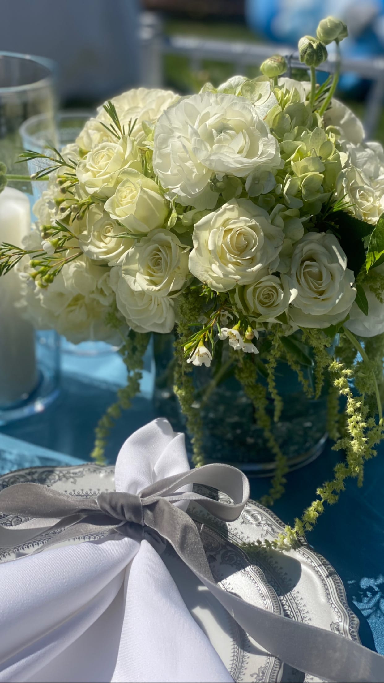 White rose and ranunculus bouquet with green accents and a gray ribbon