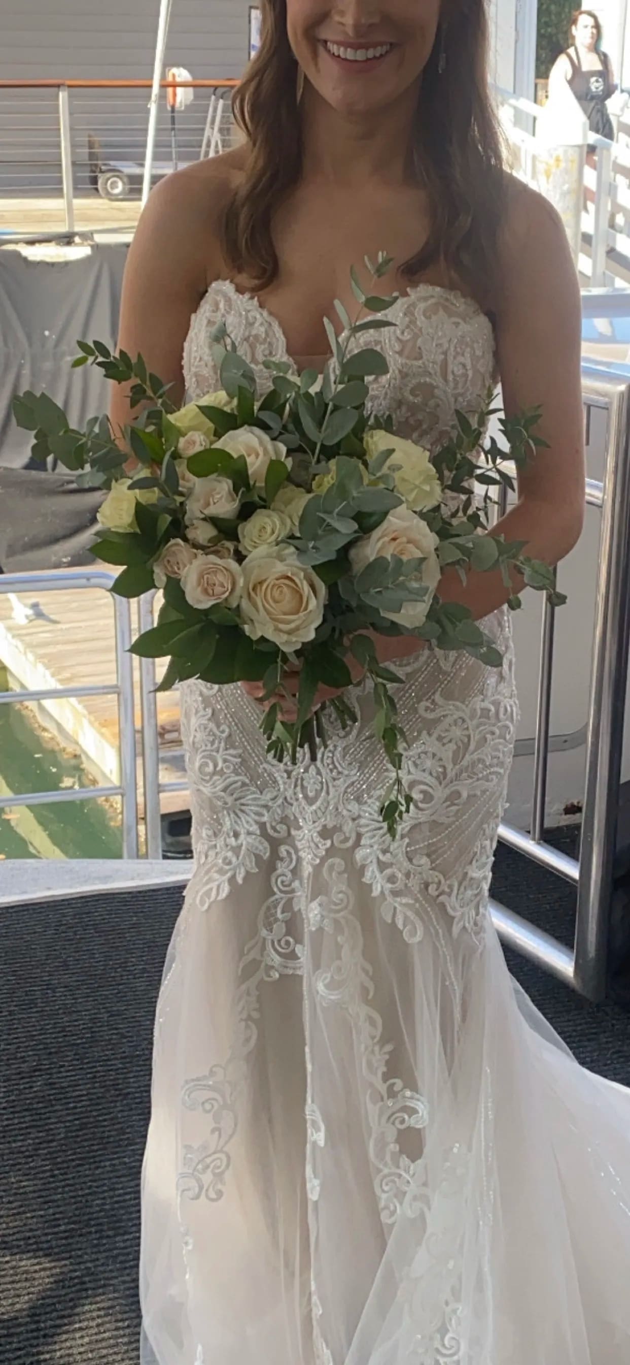 Bride holding a hand-tied bouquet of ivory roses with abundant greenery