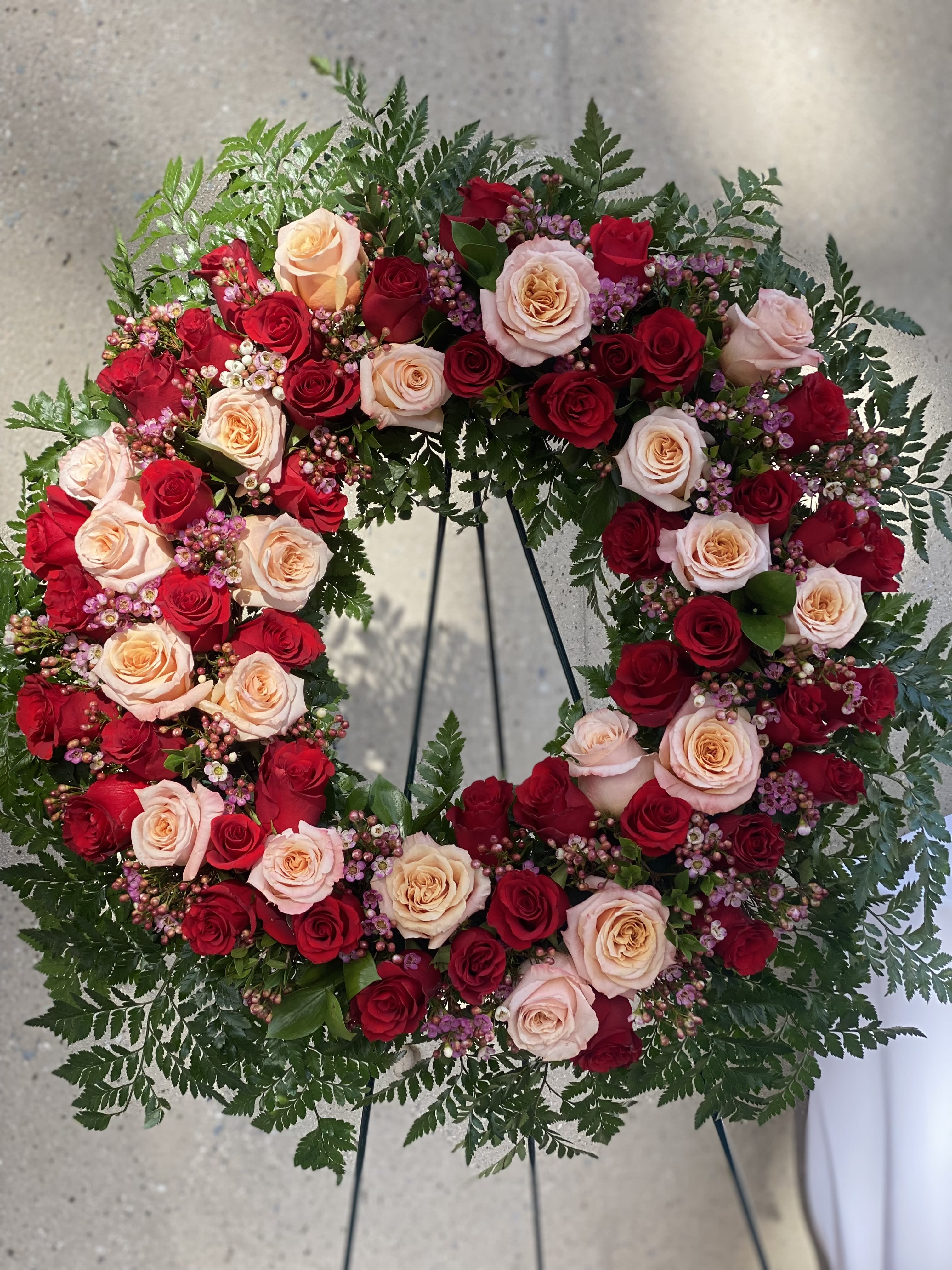 Heart-shaped wreath of red and blush roses on a stand
