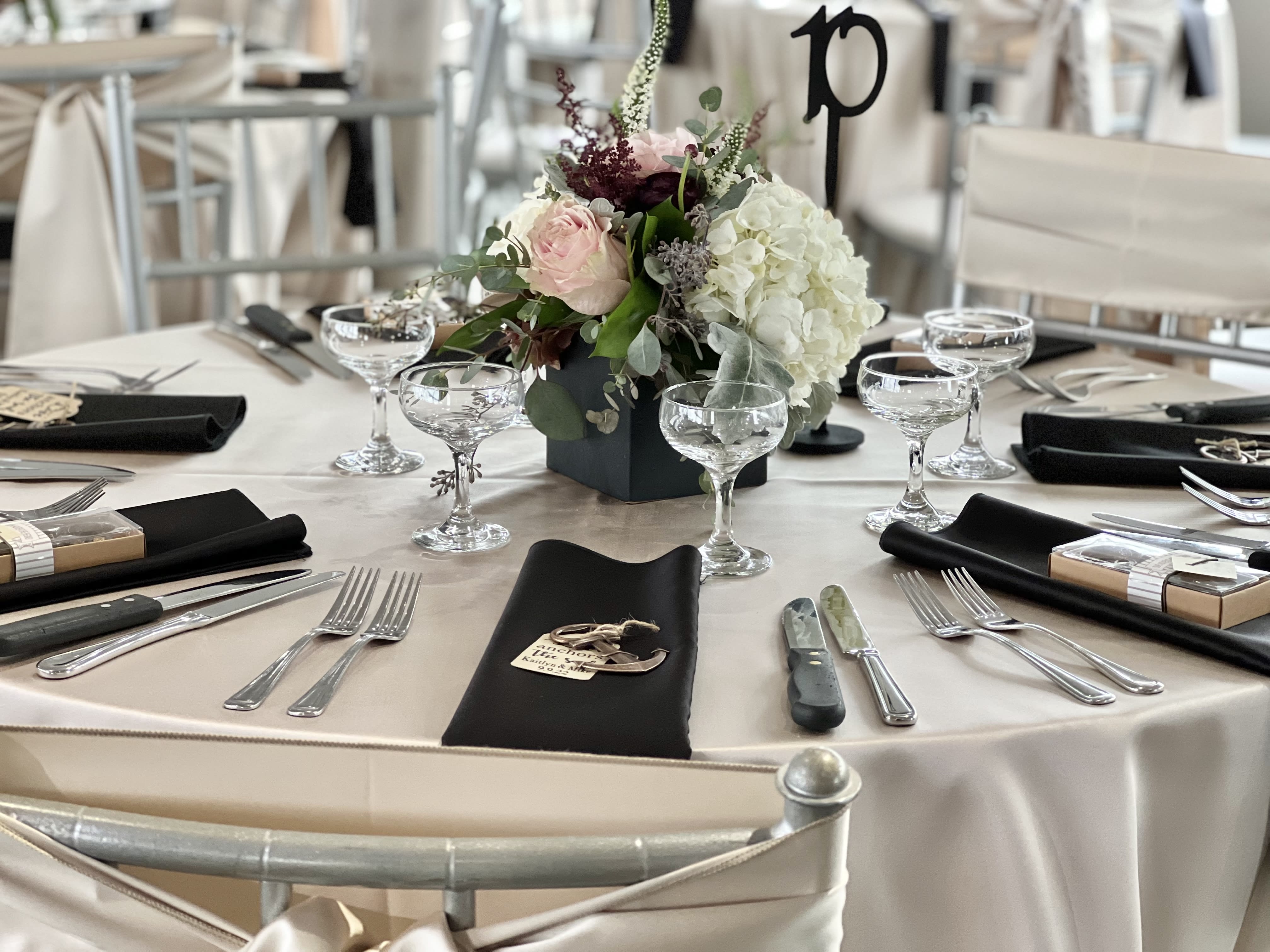 Round table centerpiece with pale pink and white flowers in a black vase