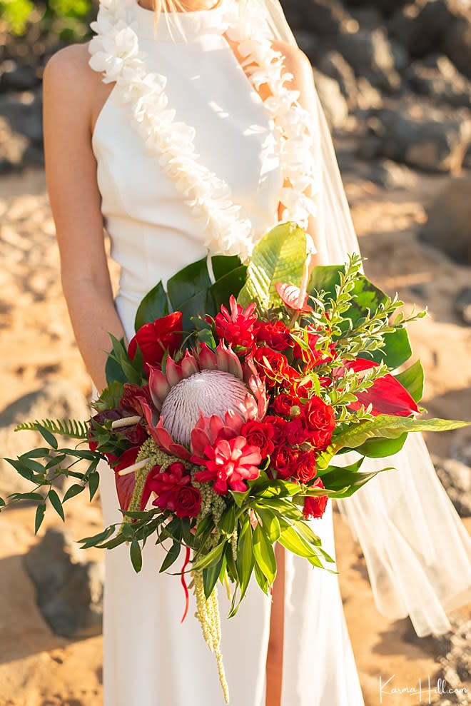 Bride holding a red tropical bouquet with a large protea bloom