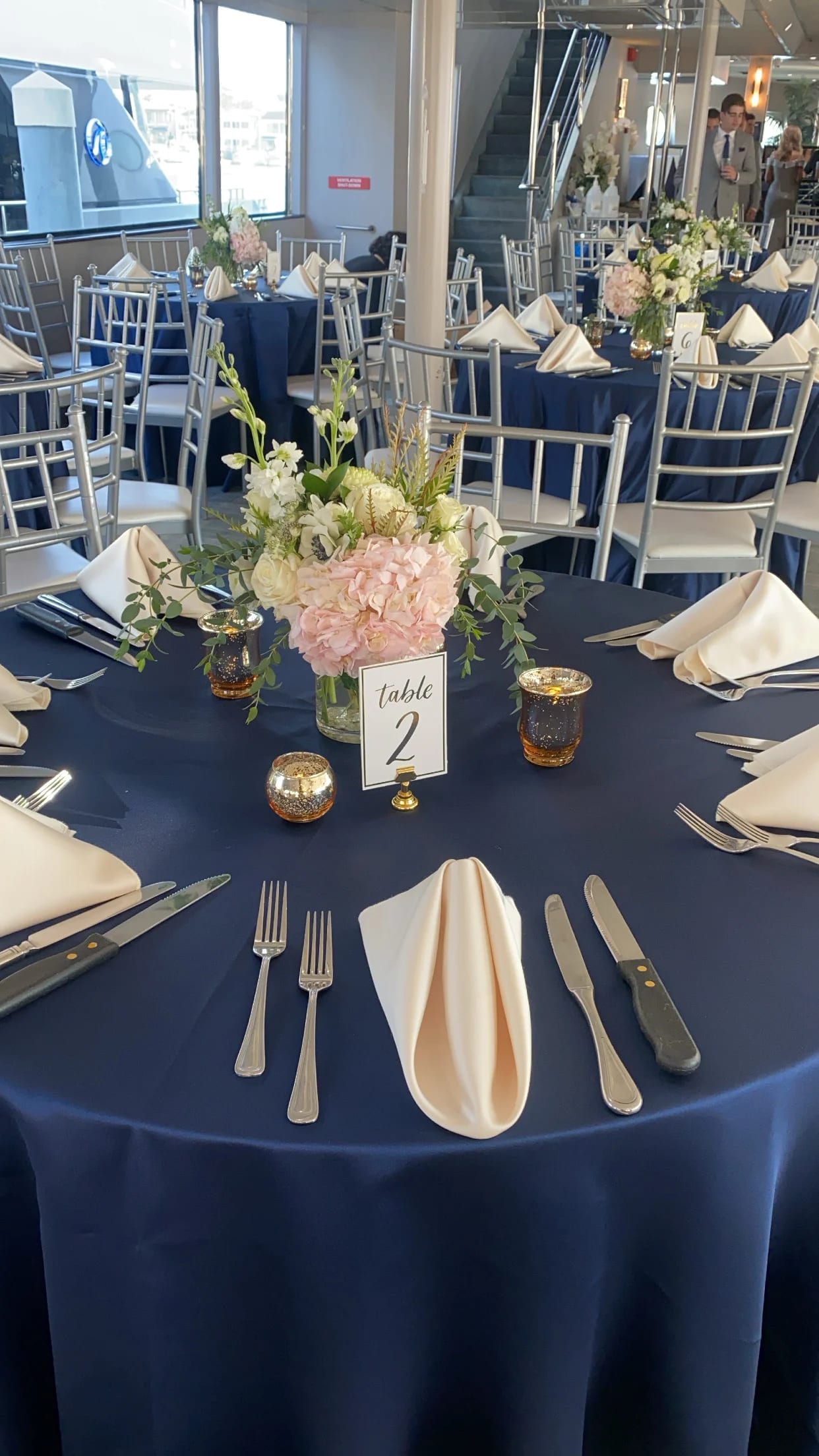 Floral centerpiece on a navy-draped table with folded cream napkins