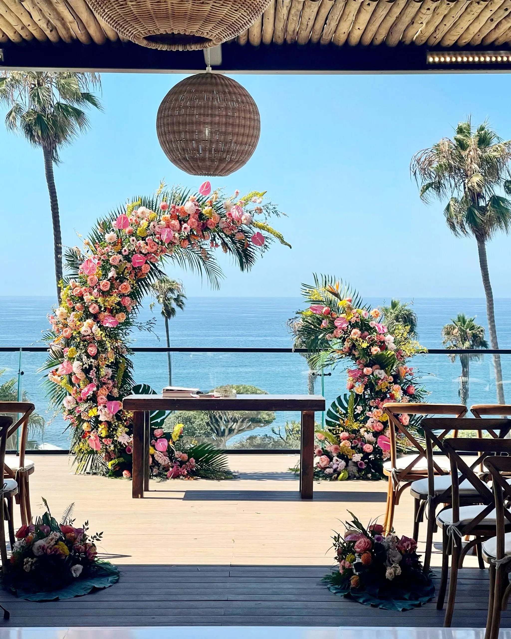 Floral wedding arch with pink and peach flowers overlooking the ocean