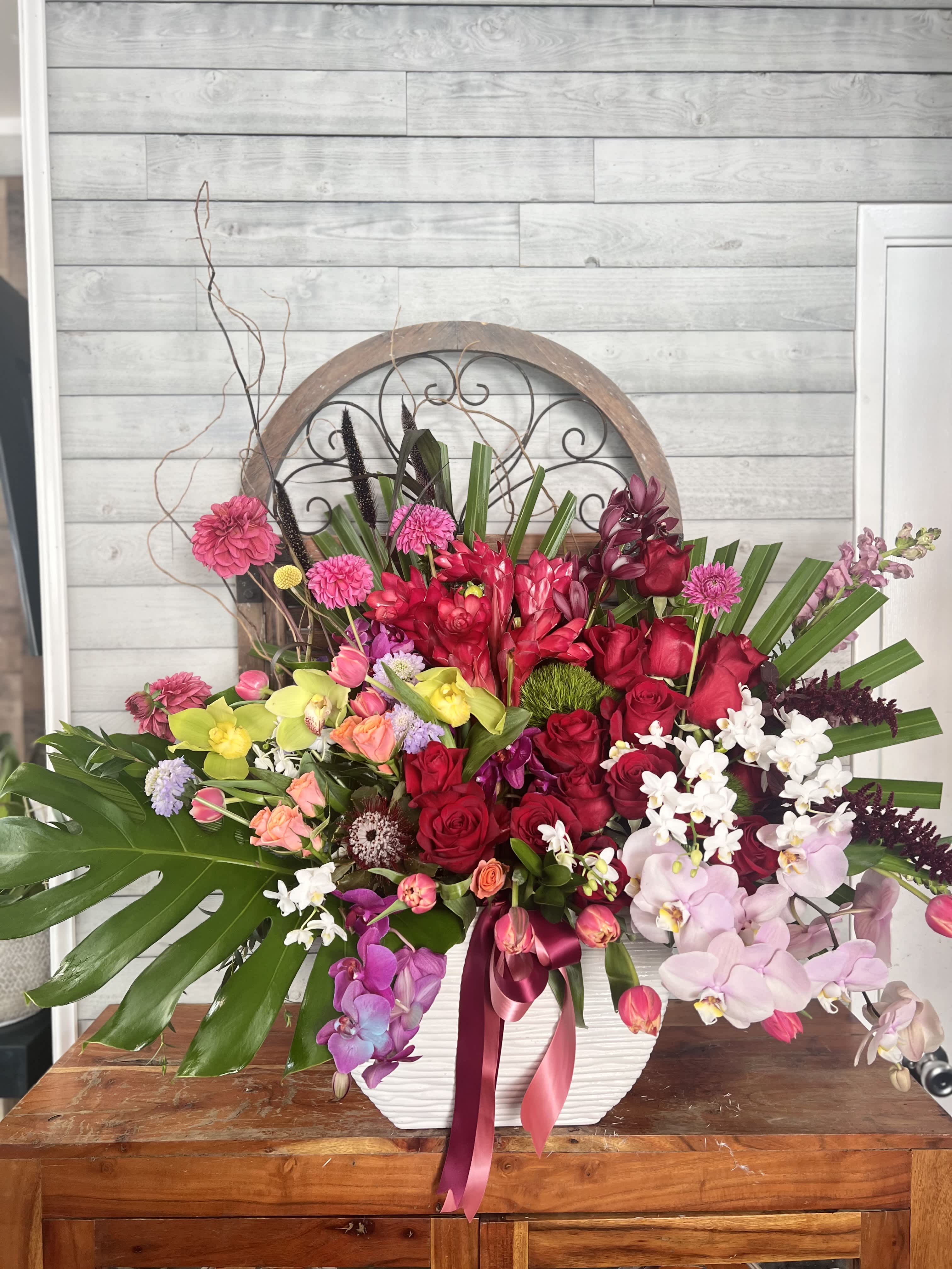 Large mixed floral arrangement in a white vase with pink, red, and white blooms