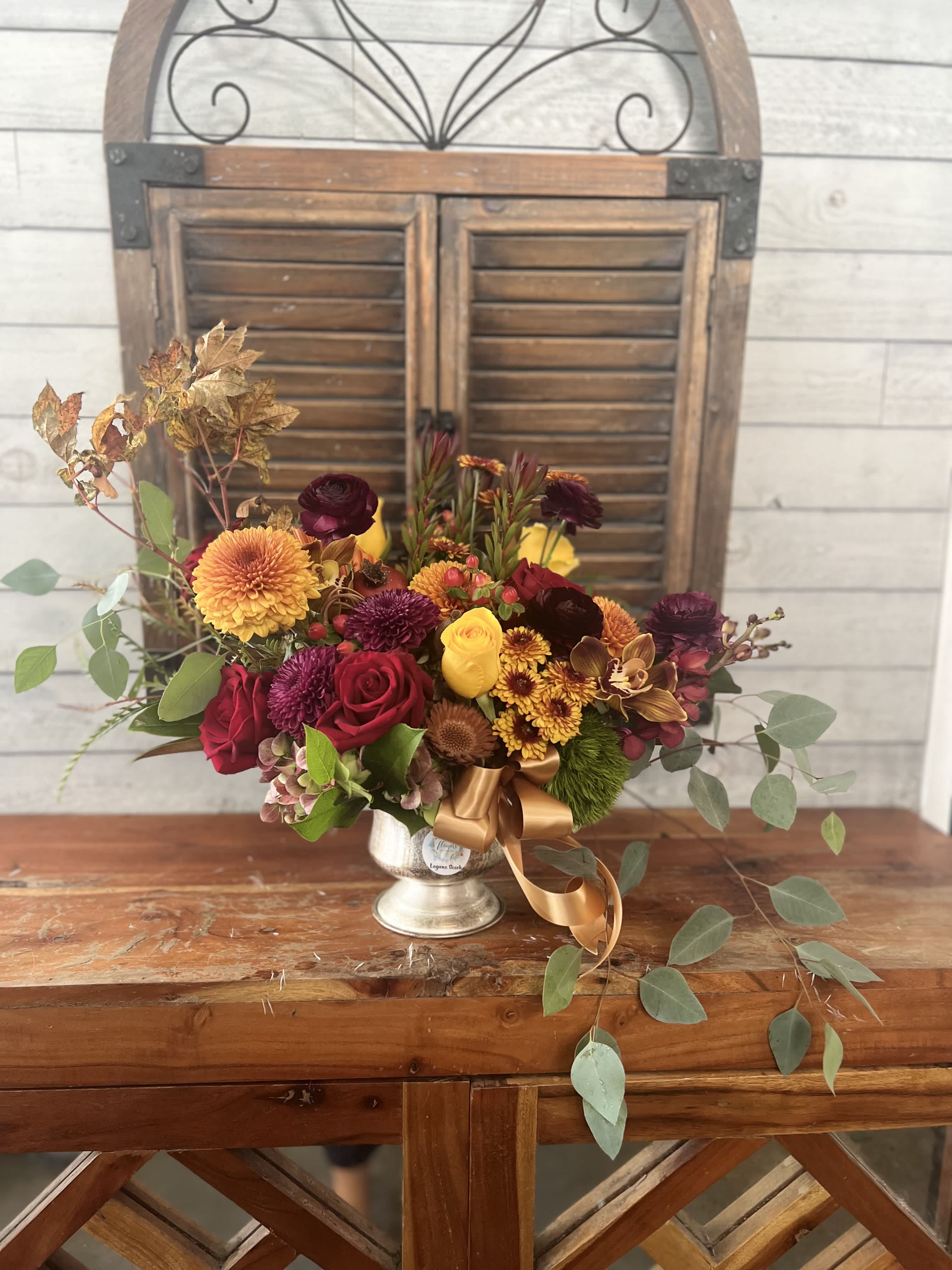Mixed bouquet in a silver vase with red, yellow, and orange flowers
