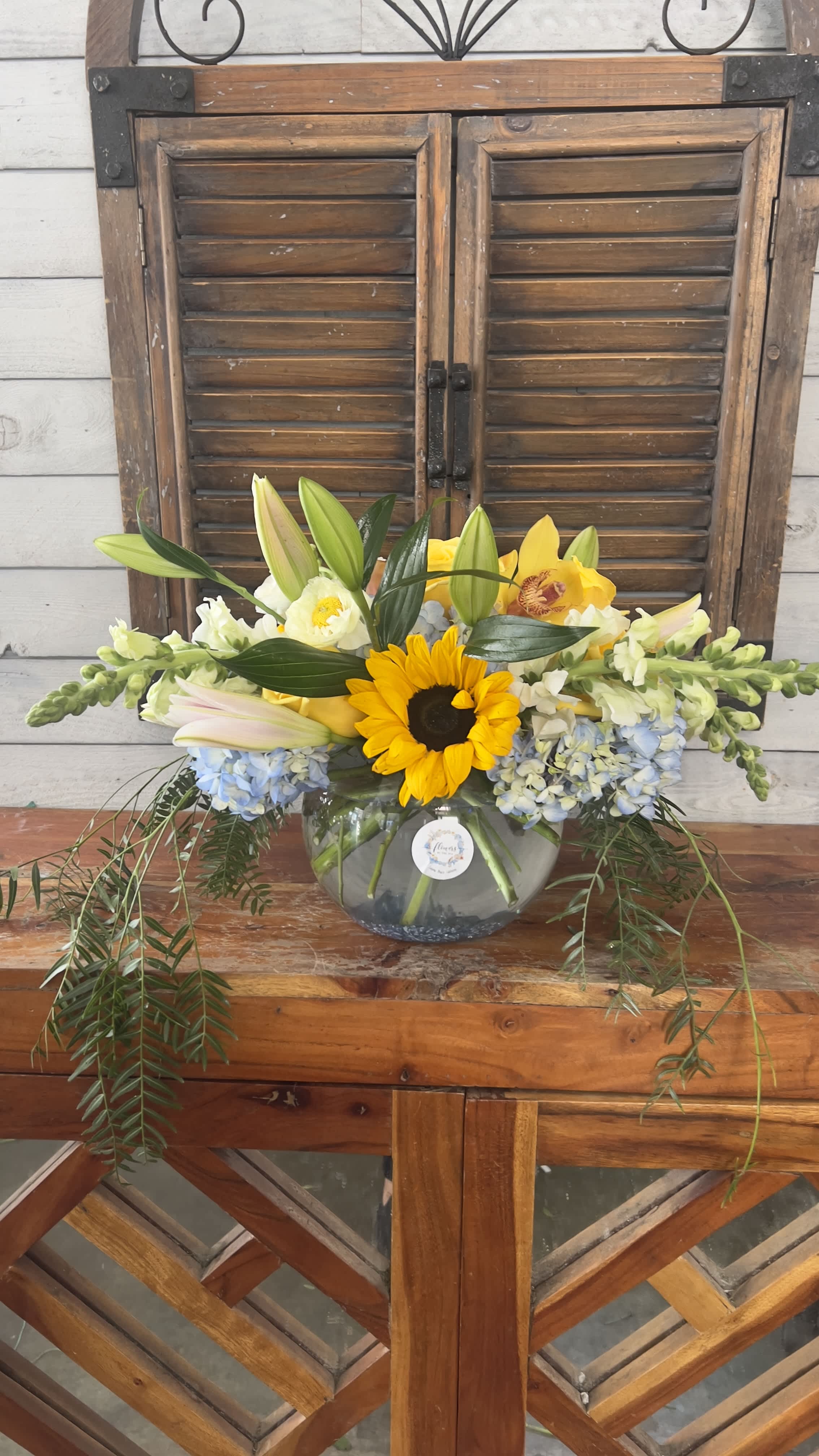 Yellow sunflower and lilies arranged in a glass bowl vase