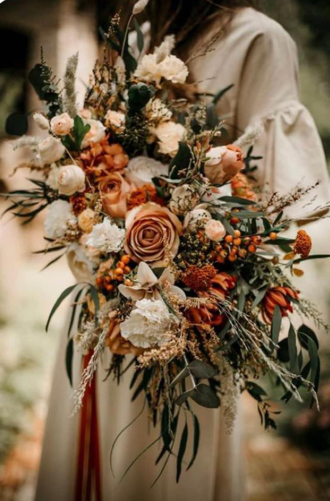 Large bouquet of peach and cream flowers with dark greenery