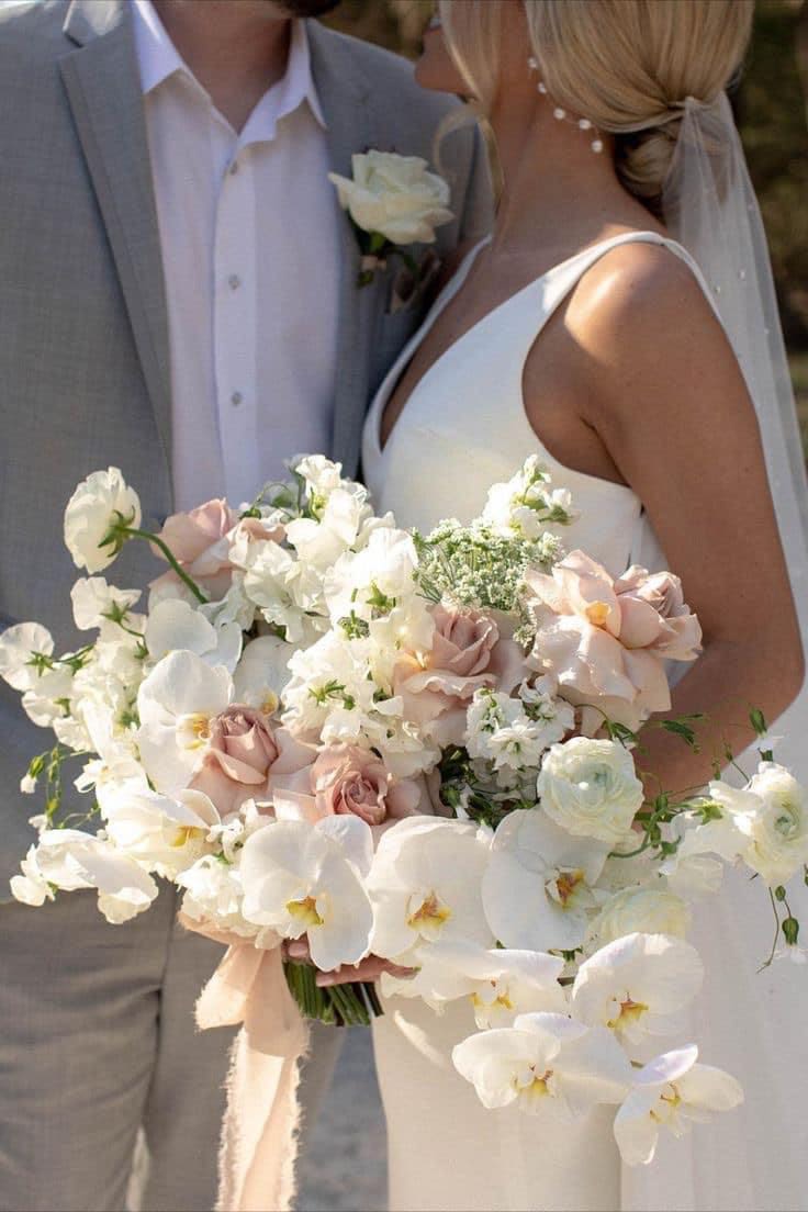 Bride holding a white and blush wedding bouquet with orchids and roses