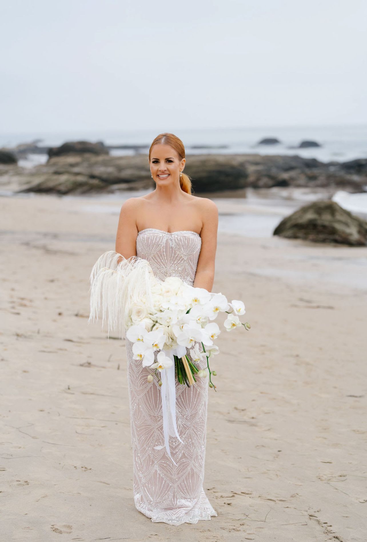 Bride holding a white orchid bouquet on a beach