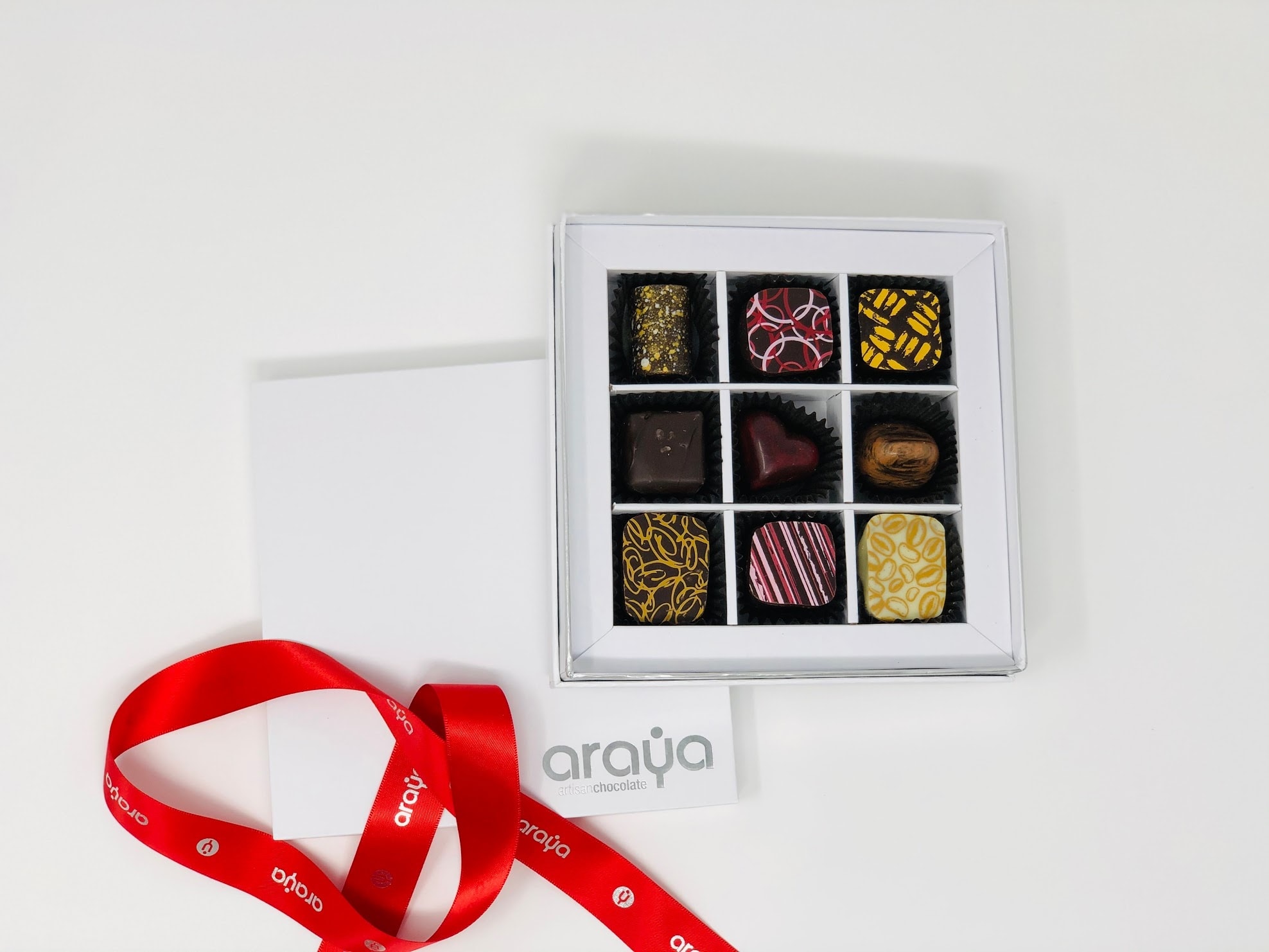 Box of assorted chocolates with a red ribbon and card