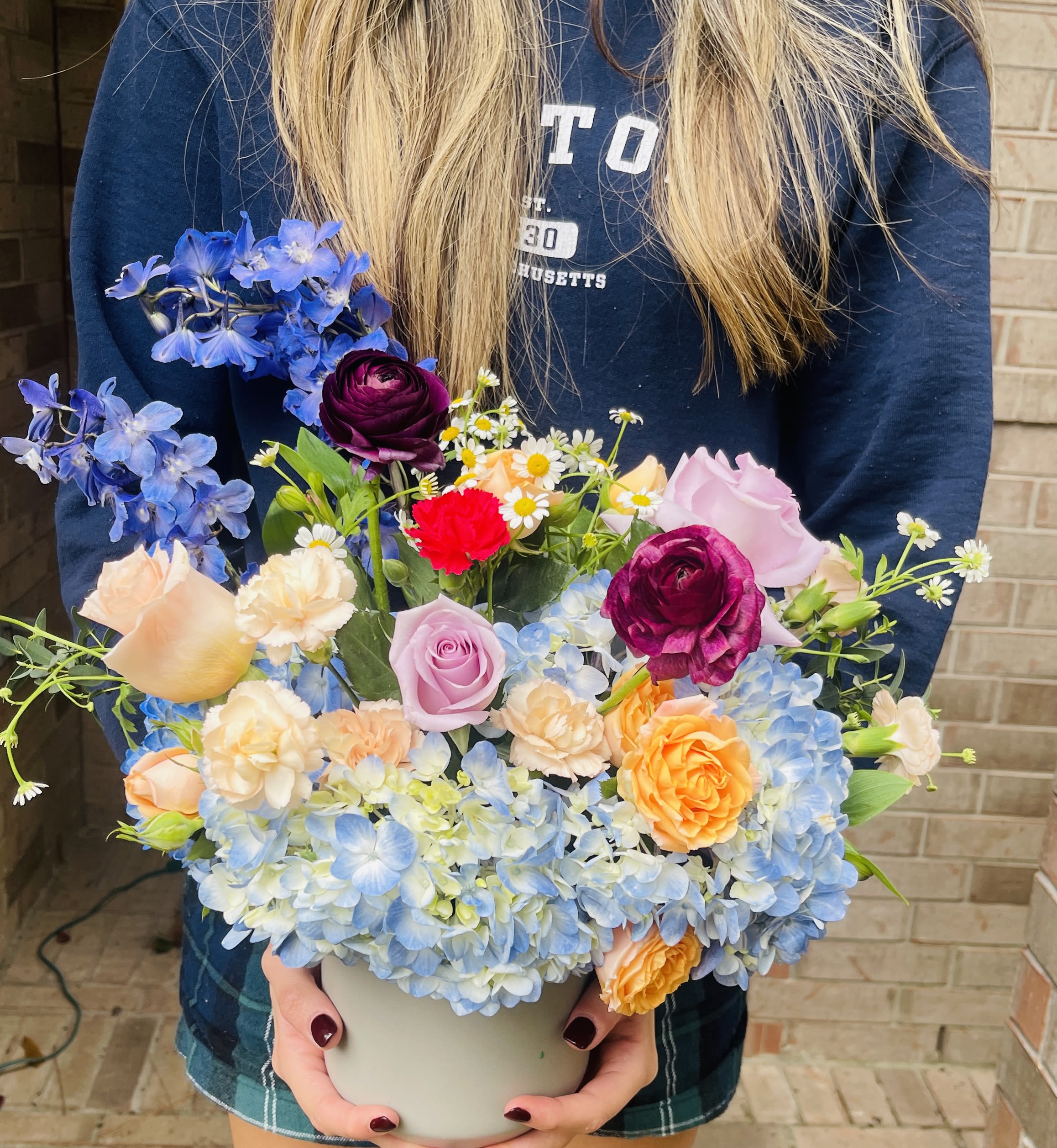 Mixed bouquet in a white vase with blue hydrangeas and roses