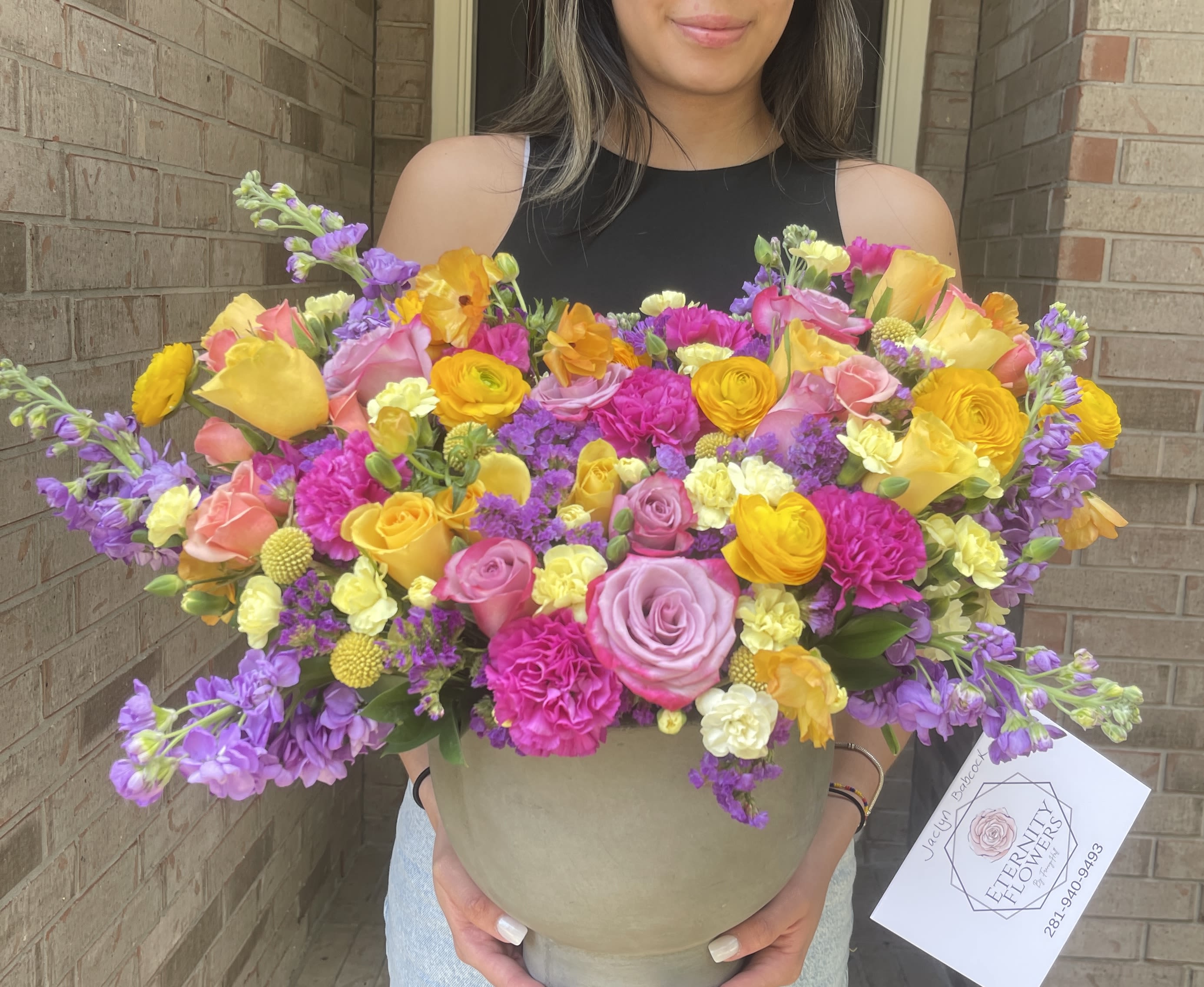 Large mixed bouquet in a beige hatbox with pink, yellow, and purple flowers