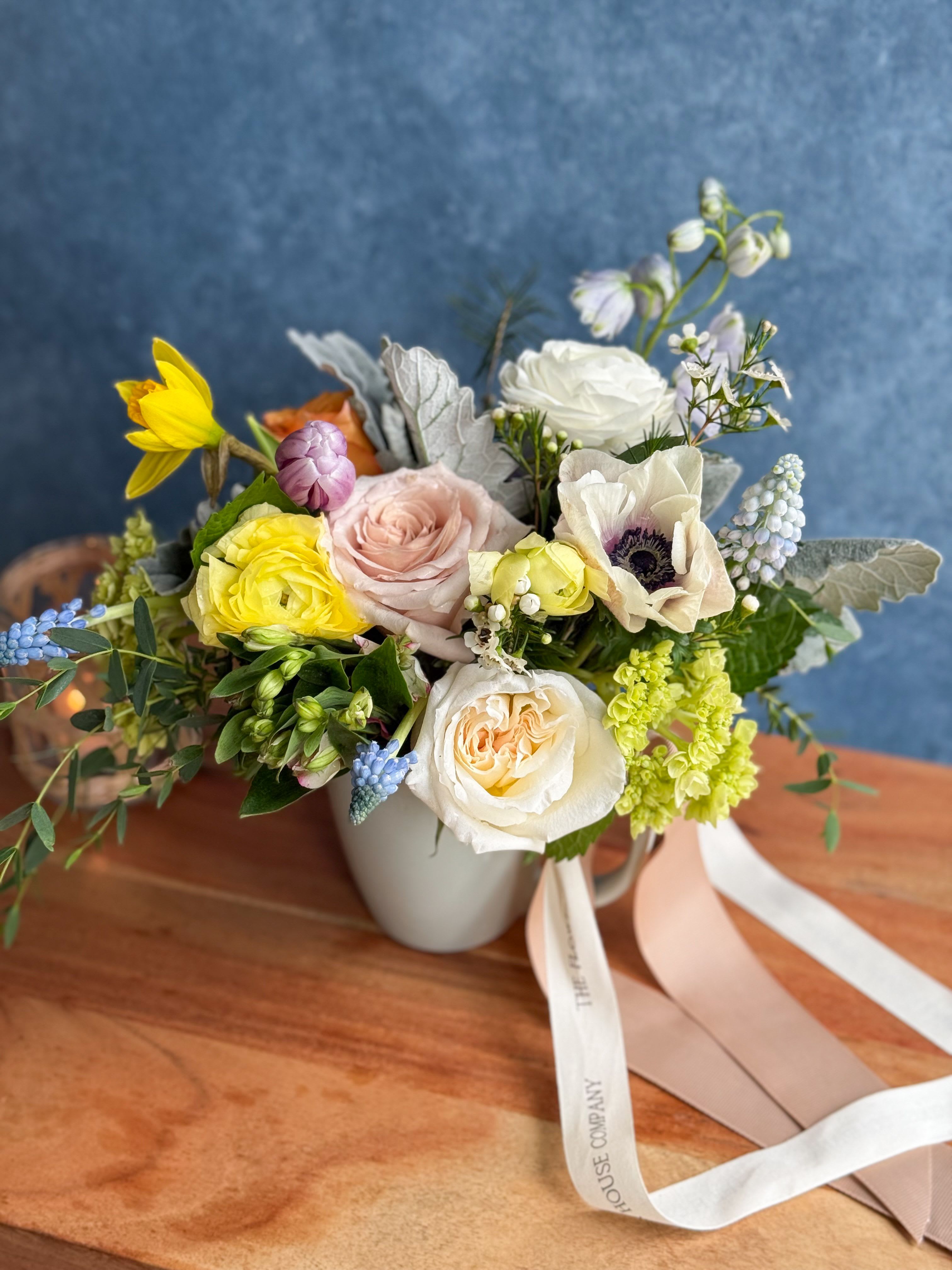 Mixed bouquet in a white mug-style vase with pastel roses and anemones