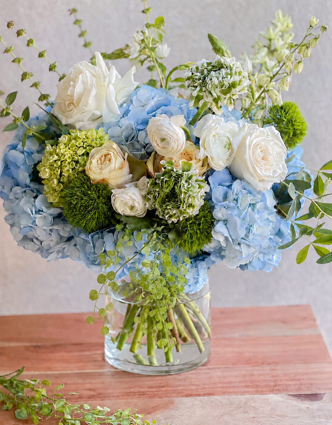 Blue hydrangeas and white roses arranged in a clear glass vase