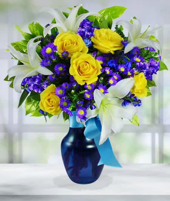 Bouquet of yellow roses, purple flowers, and white lilies in a blue vase