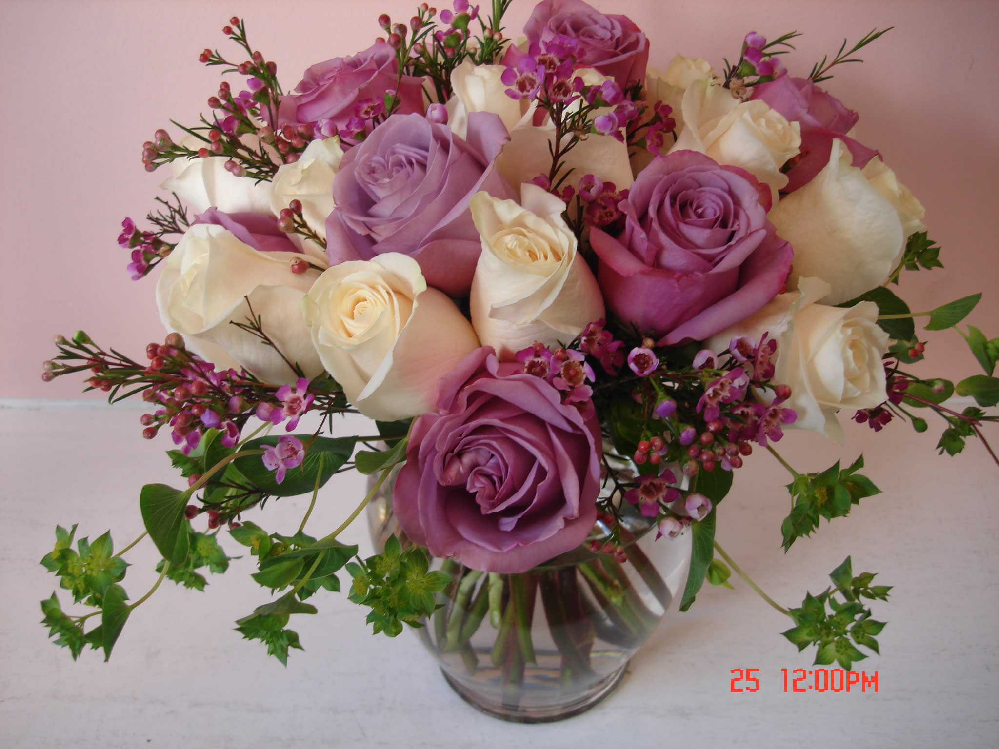 Bouquet of pink, lavender, and white roses in a clear glass vase