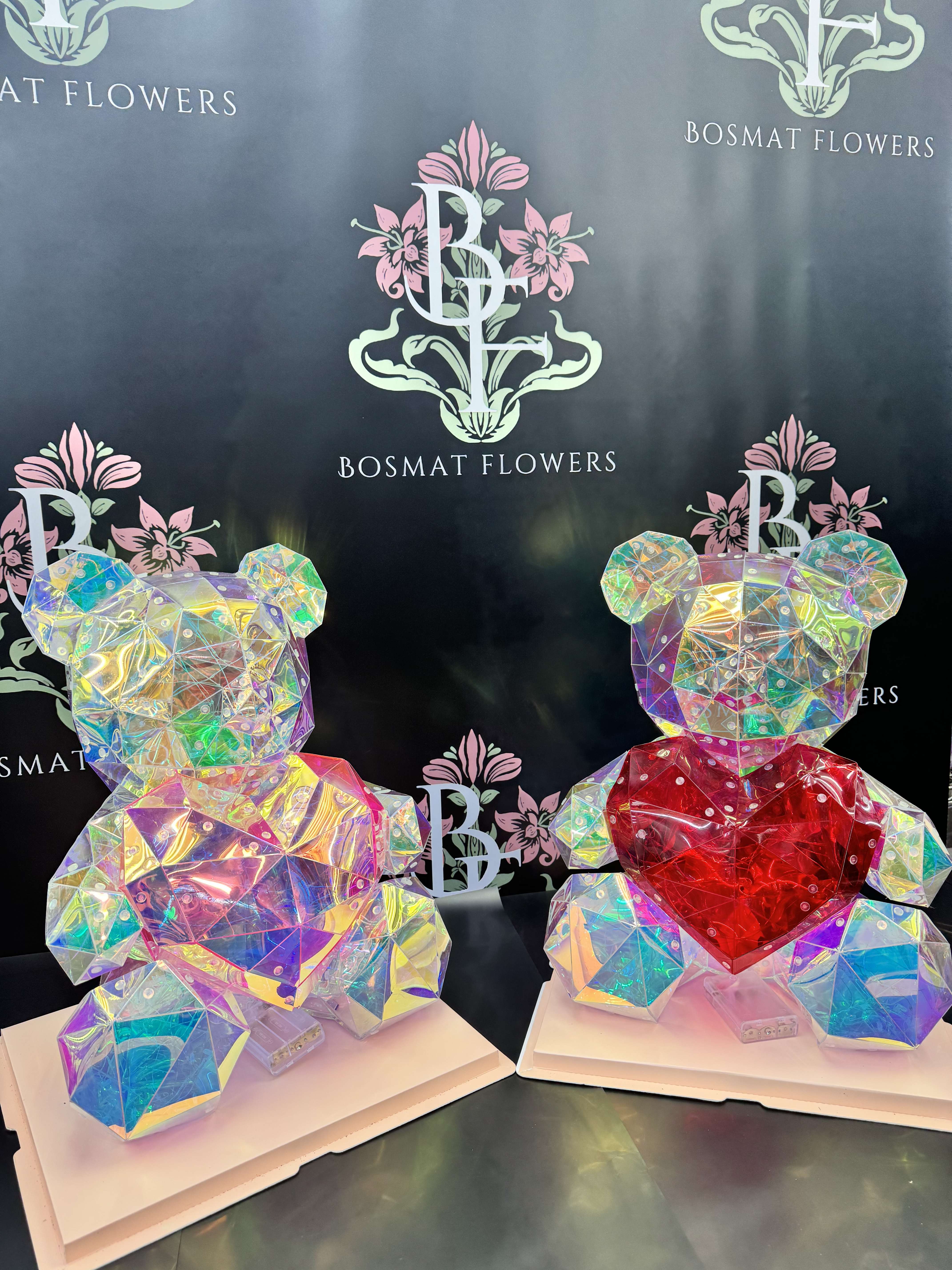 Two iridescent teddy bear sculptures with heart accents on white bases