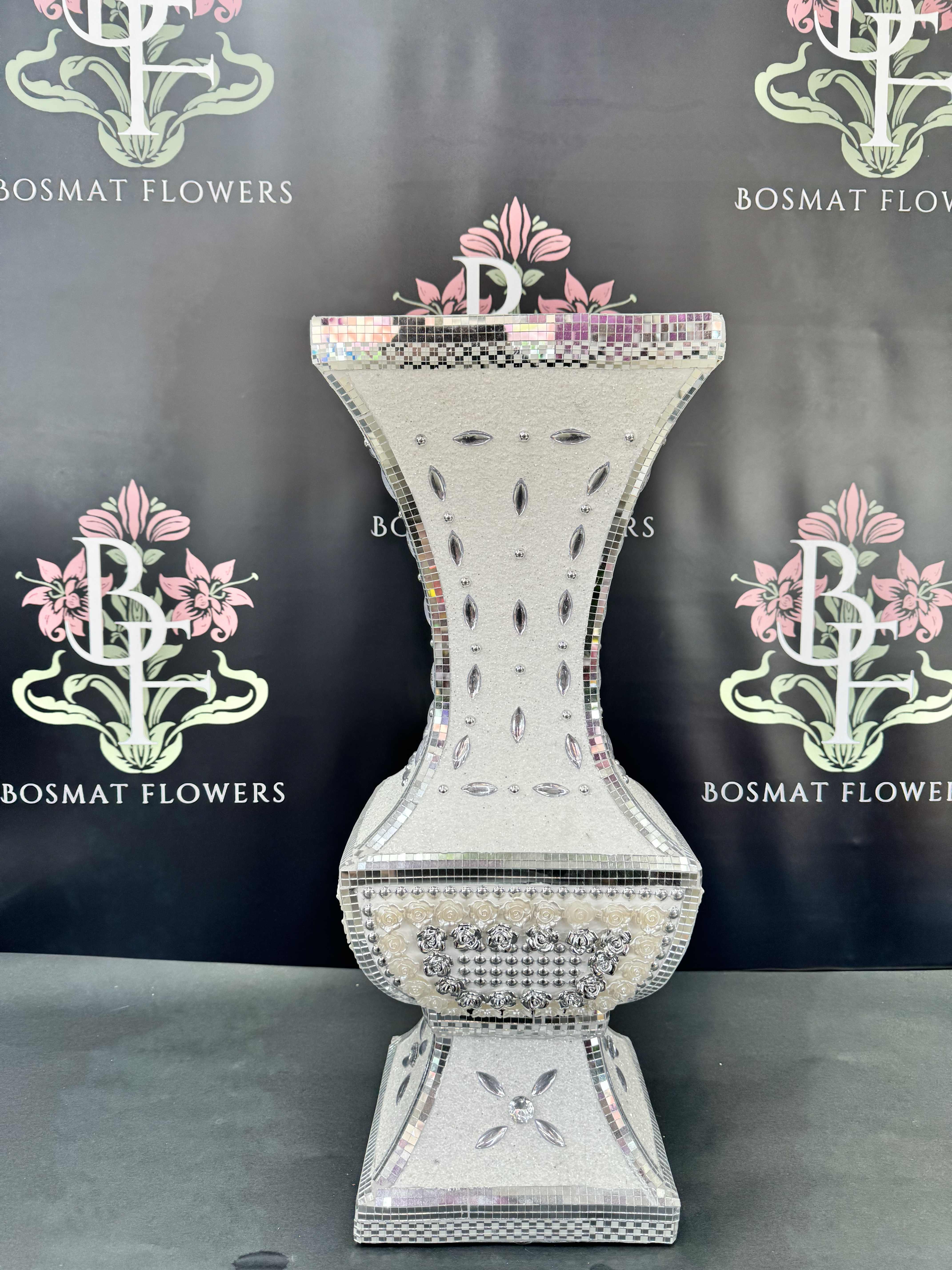 Decorative silver mosaic pedestal vase on a black backdrop