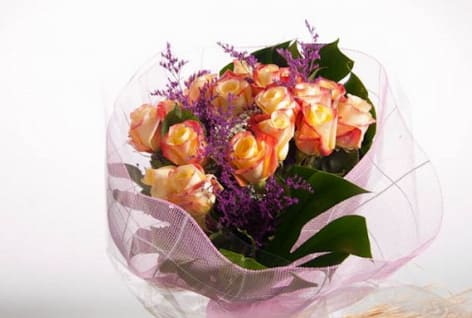 Bouquet of peach and yellow roses with purple filler flowers