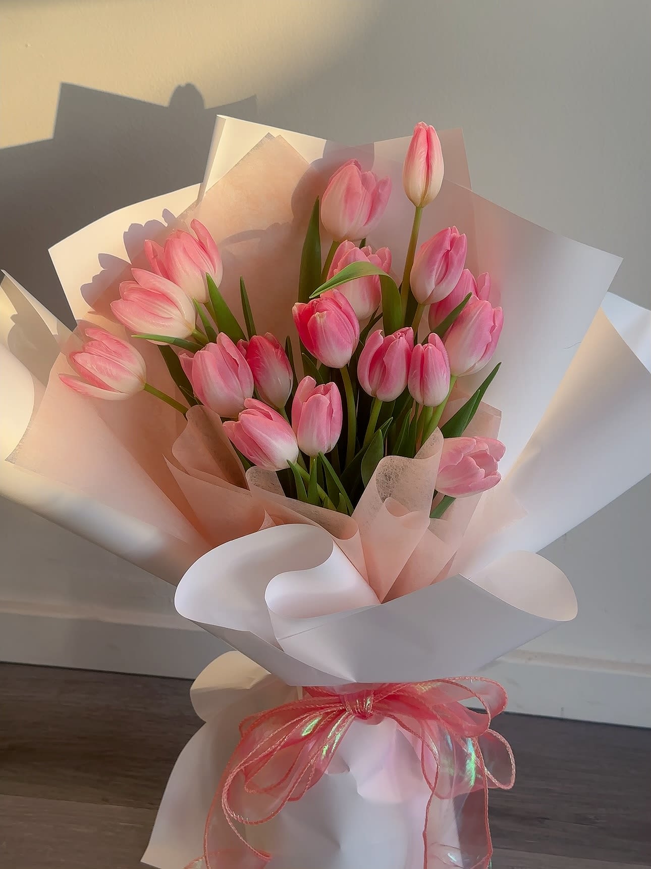 Pink tulip bouquet wrapped in white and blush paper with a pink ribbon