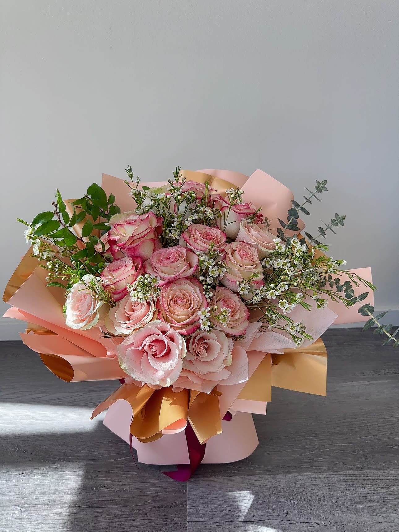 Pink and cream rose bouquet wrapped in peach paper