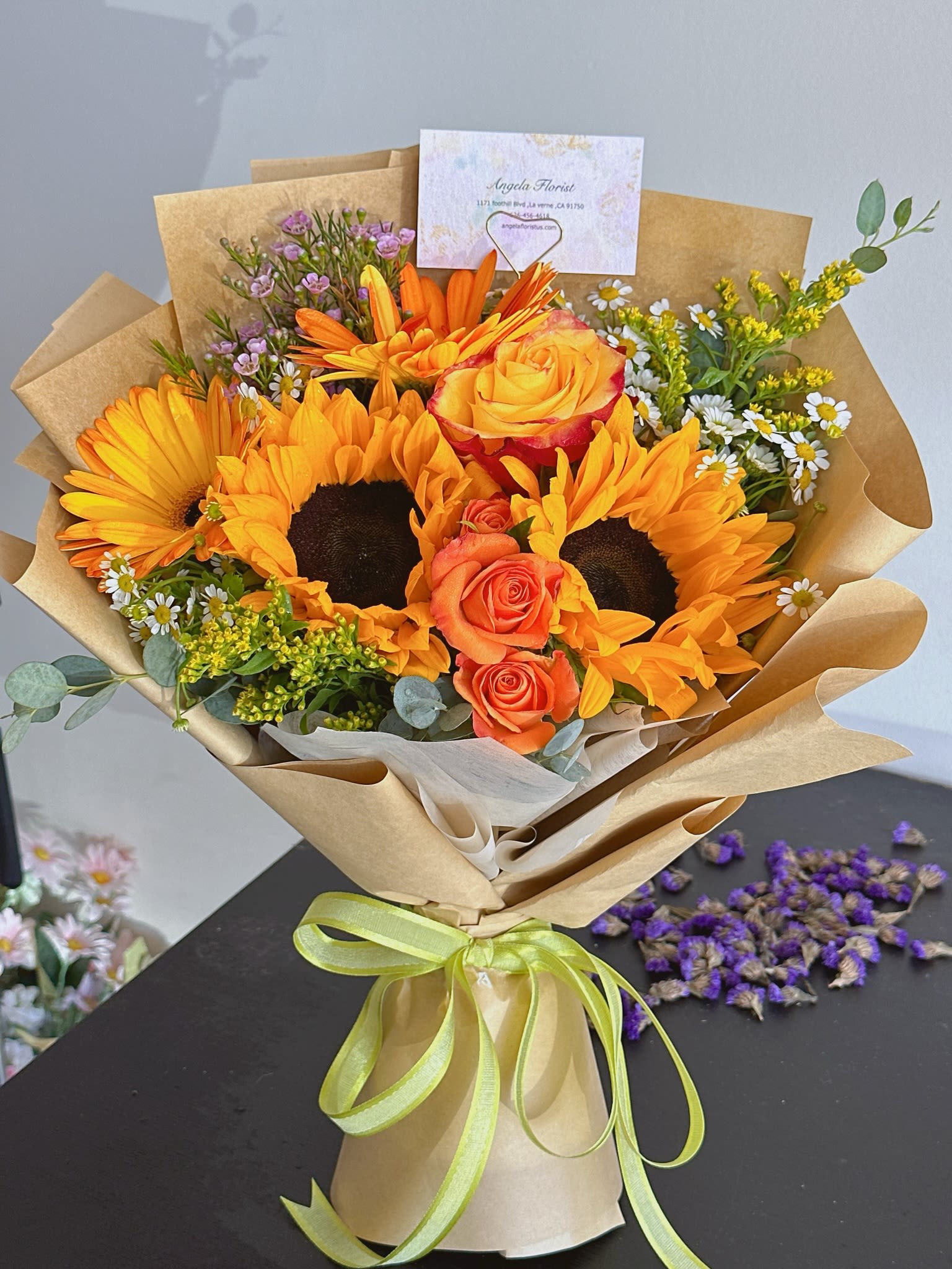 Bouquet of sunflowers and orange roses wrapped in kraft paper