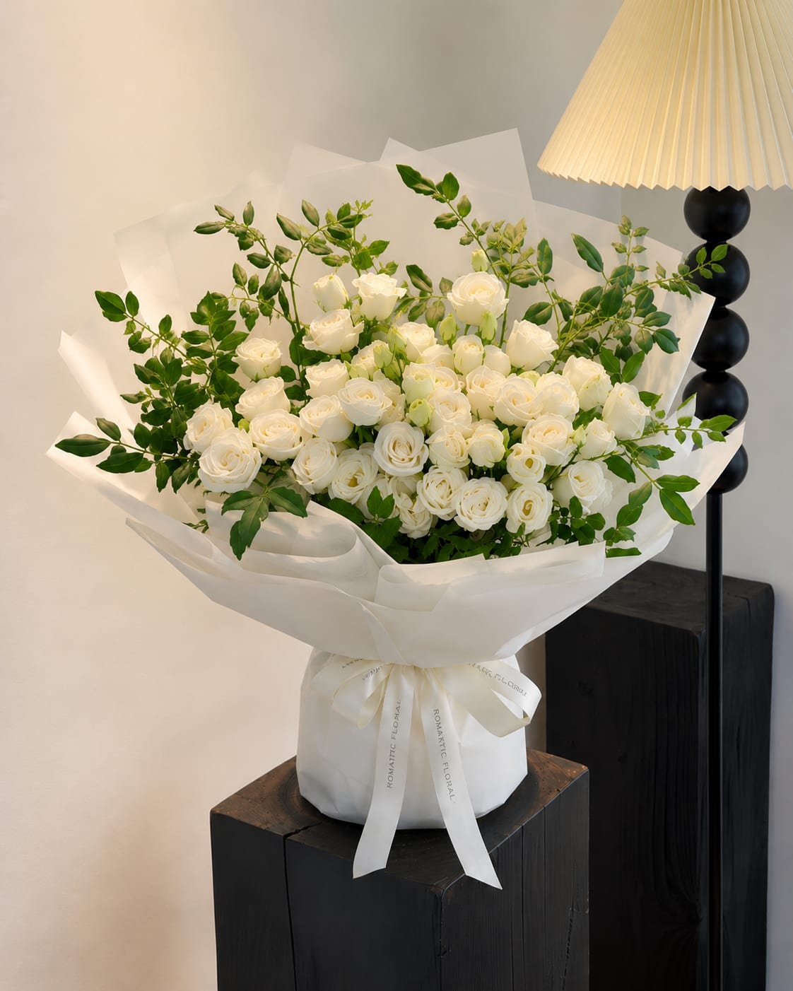 Moonlight Bloom （White Lisianthus Bouquet） - Moonlight Bloom  An elegant arrangement of white lisianthus paired with fresh seasonal greenery fillers, wrapped in layers of soft ivory paper.  Inspired by the quiet beauty of moonlight, this bouquet brings a sense of calm, grace, and timeless romance. Its clean white palette and natural textures make it a thoughtful gift for any meaningful occasion.  Details  * White Lisianthus * Seasonal Greenery Fillers * Signature Ivory Wrap * Satin Ribbon Finish  Flower varieties may vary slightly according to seasonal availability. Substitutions will always be made with blooms of equal or greater value while preserving the original aesthetic.