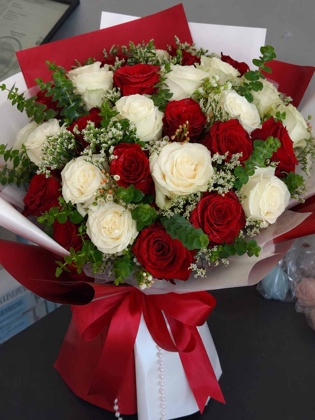 Crimson &amp; Ivory Romance - Crimson &amp; Ivory Romance features 15 premium red roses and 15 premium white roses, accented with delicate seasonal flowers and fresh greenery, then elegantly wrapped in premium paper. The beautiful contrast of red and white symbolizes love, passion, purity, and everlasting devotion, making this bouquet a perfect gift for anniversaries, birthdays, Valentine’s Day, or any romantic occasion.  Available in Standard, Deluxe, and Premium sizes. The standard rose colors are red and white, but rose colors, wrapping paper, and ribbon can all be customized upon request. Simply leave your preferences in the order notes at checkout. Each bouquet is handcrafted with fresh flowers, and slight seasonal variations may occur while maintaining the same beautiful design.