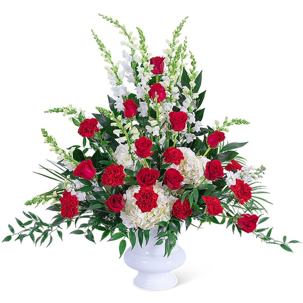 Red roses and white flowers arranged in a white urn vase