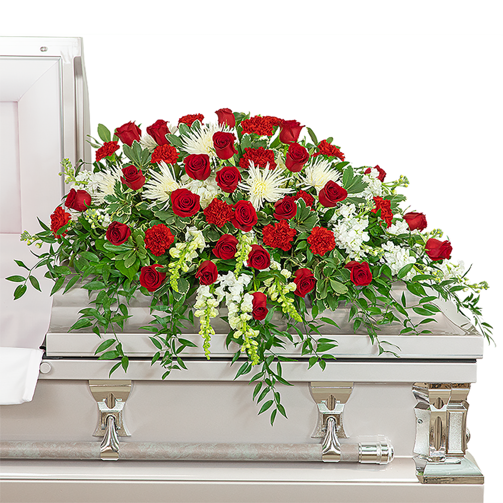 Red roses and white flowers arranged on a white casket