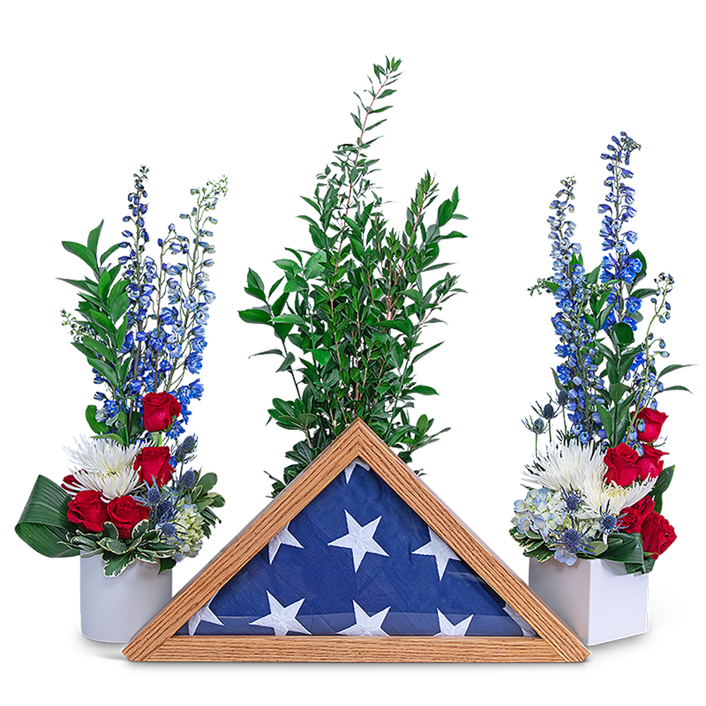Red, white, and blue floral tribute with a folded flag in a wooden frame