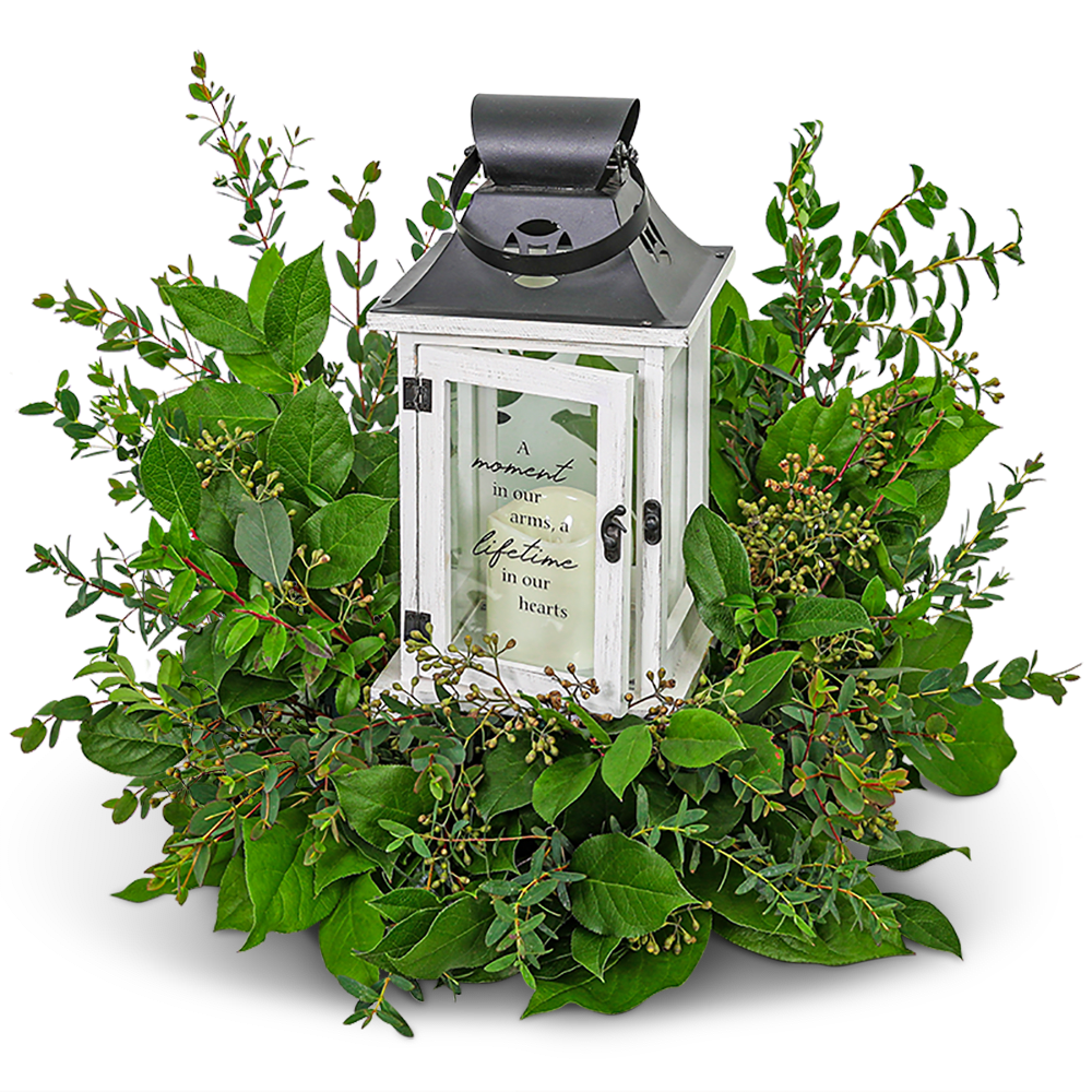 White lantern centerpiece surrounded by green foliage