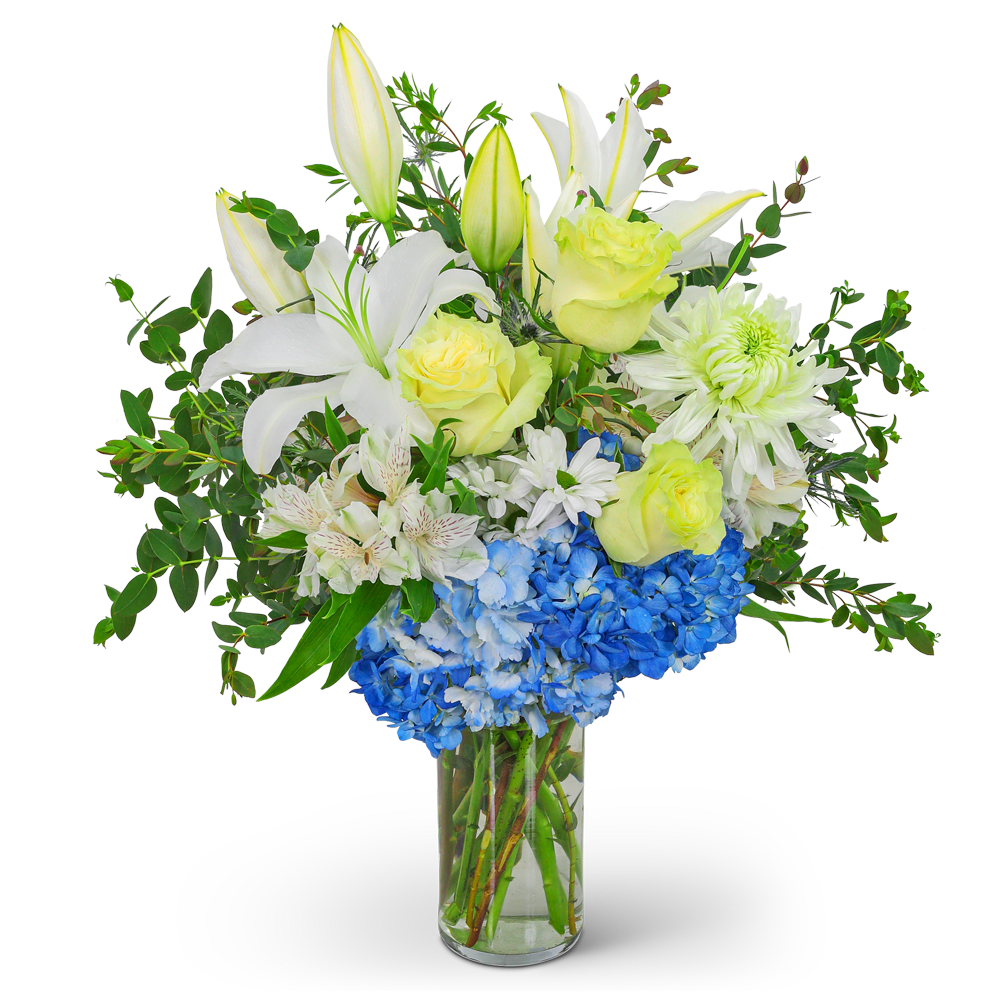White lilies, yellow roses, and blue hydrangeas in a clear glass vase